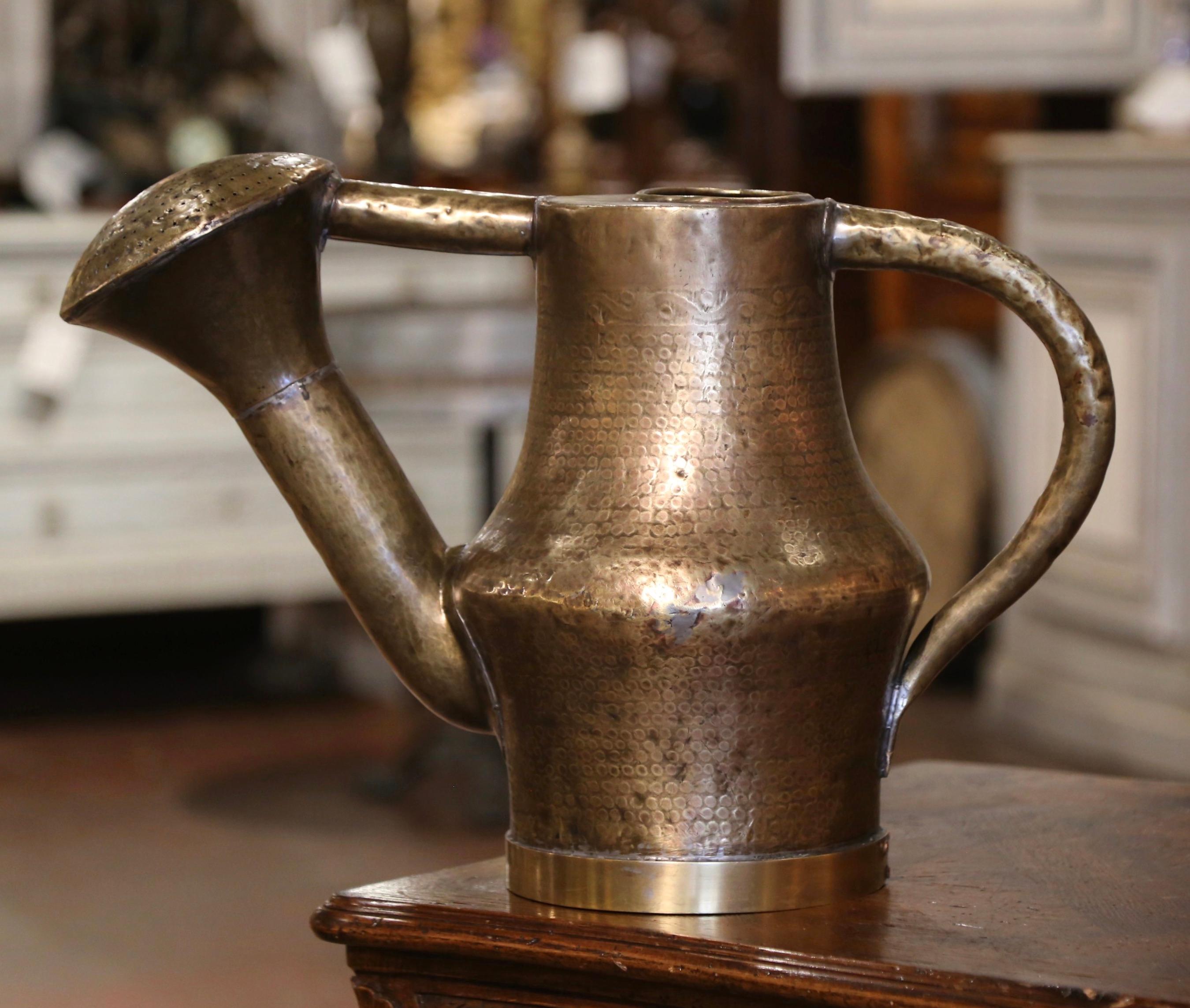 Decorate kitchen cabinets with this large antique water can. Hand crafted in France circa 1860, and built of brass, the hammered metal construction gives this watering can a charming and unique character. Designed with a gracefully curved handle and