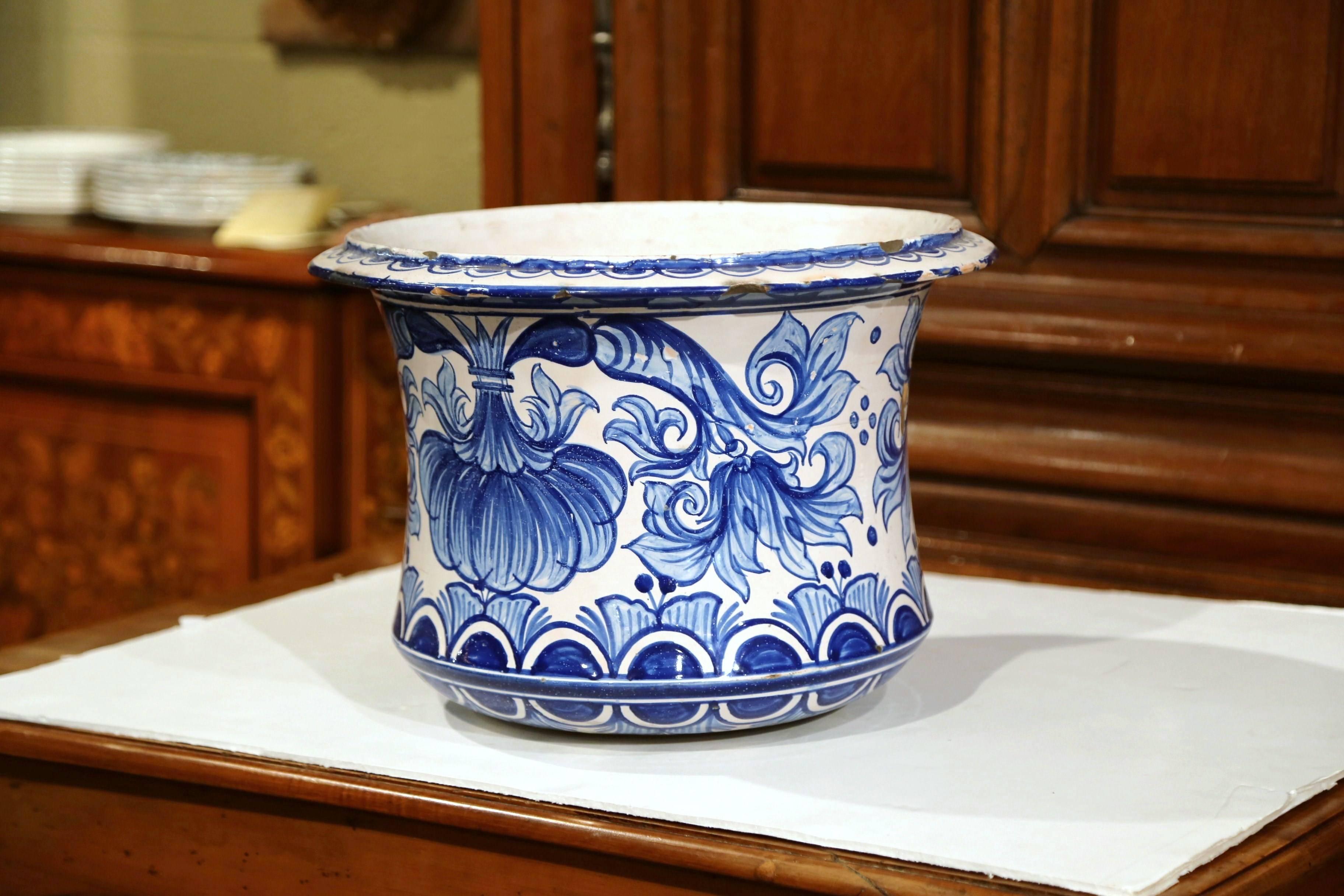 This elegant, antique faience planter was crafted in Nevers, France, circa 1850. The large, porcelain cache-pot features hand-painted flowers and leaves in a traditional blue and white palette. The ceramic vase is in good condition commensurate with