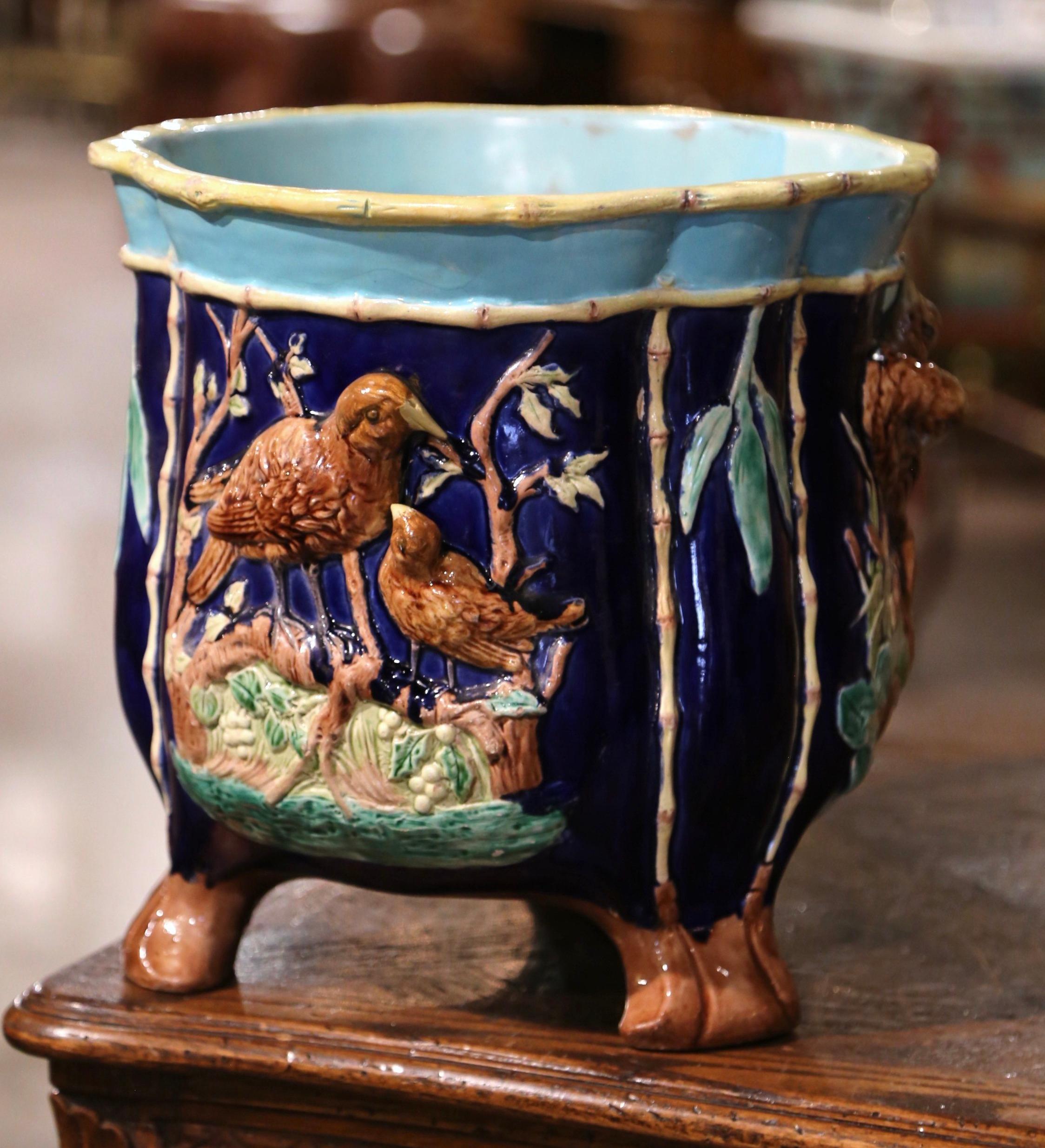 Decorate a tabletop with this colorful, antique Majolica planter. Sculpted in France circa 1860, the ceramic vase stands on three bracket feet over a round and bombe body topped with a scalloped edge. The cache pot is decorated with three medallions