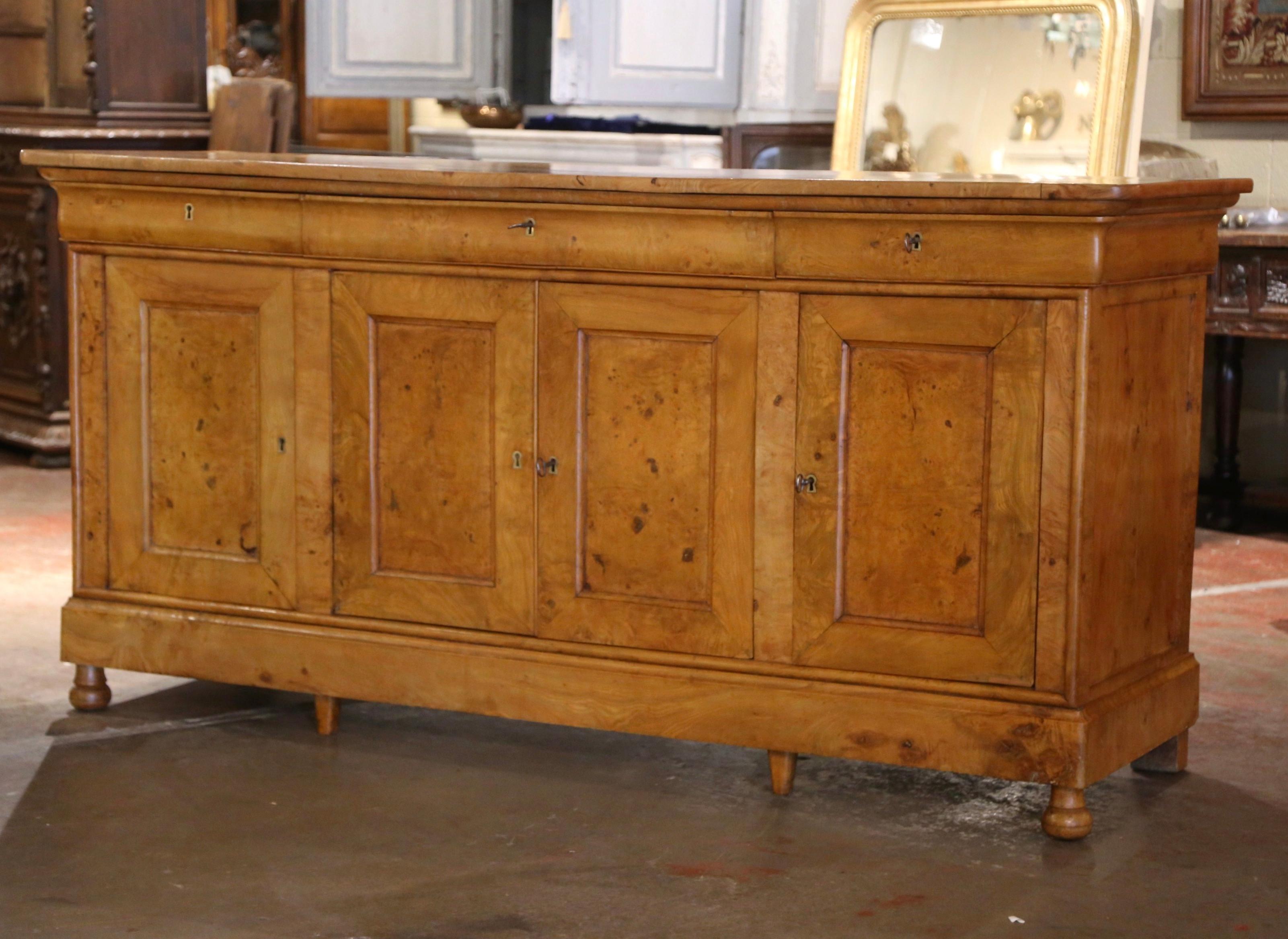 Decorate a dining or living room with this elegant antique buffet! Crafted in France, circa 1850 and built of elm wood, the eight-leg cabinet stands on bun feet over a thick straight plinth apron. The rectangular case cabinet is fitted with three