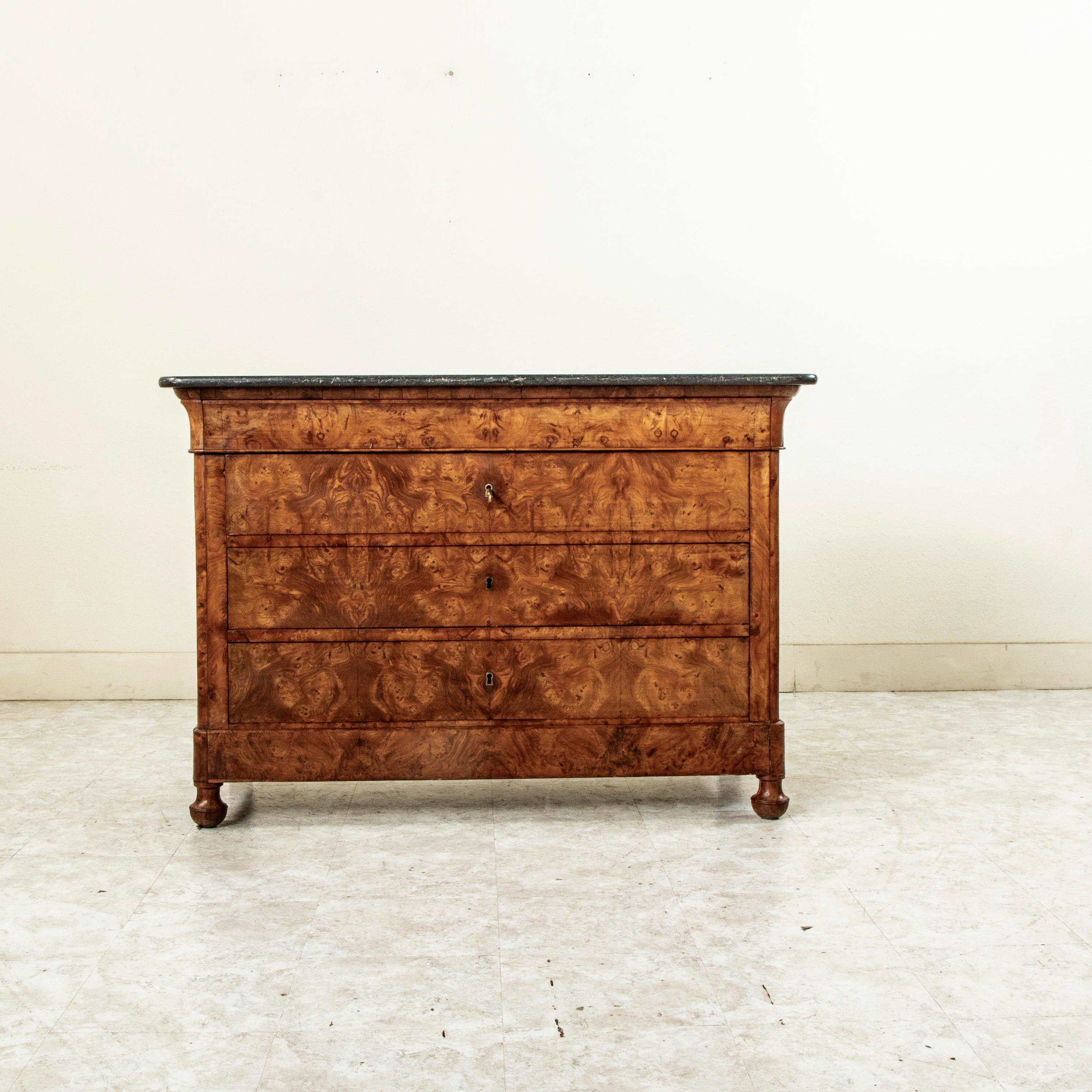 Esta cómoda o cajonera de época Louis Philippe por excelencia muestra la artesanía ejemplar del siglo XIX con una fachada de olmo burl y laterales de paneles de olmo macizo. La pieza está rematada con una encimera de mármol negro de doble bisel. Un