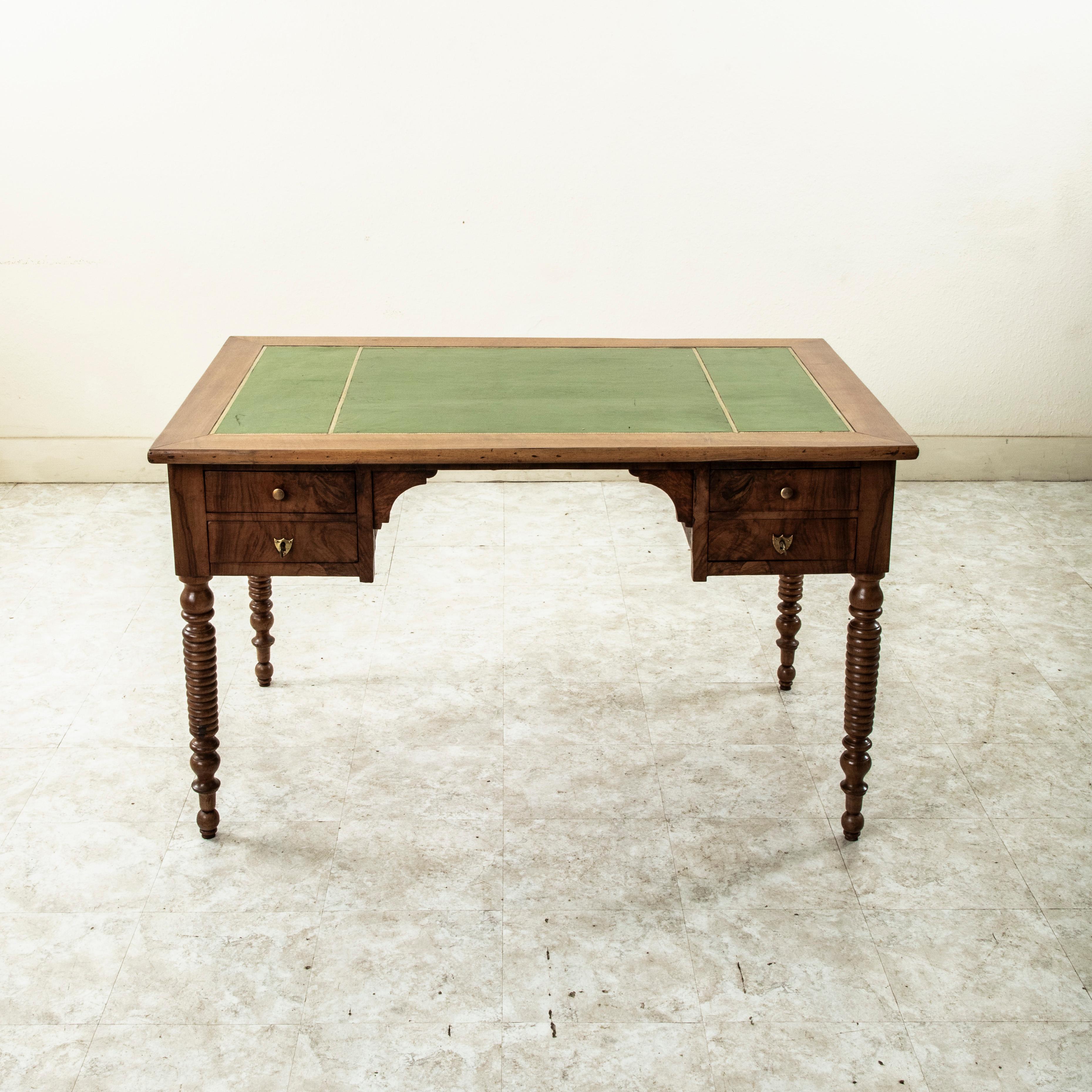 Dieser französische Nussbaumschreibtisch aus dem neunzehnten Jahrhundert der Louis-Philippe-Periode ist mit einer goldverzierten grünen Lederplatte ausgestattet. Zwei Schubladen mit Schwalbenschwanzkonstruktion passen in die Schürze auf beiden