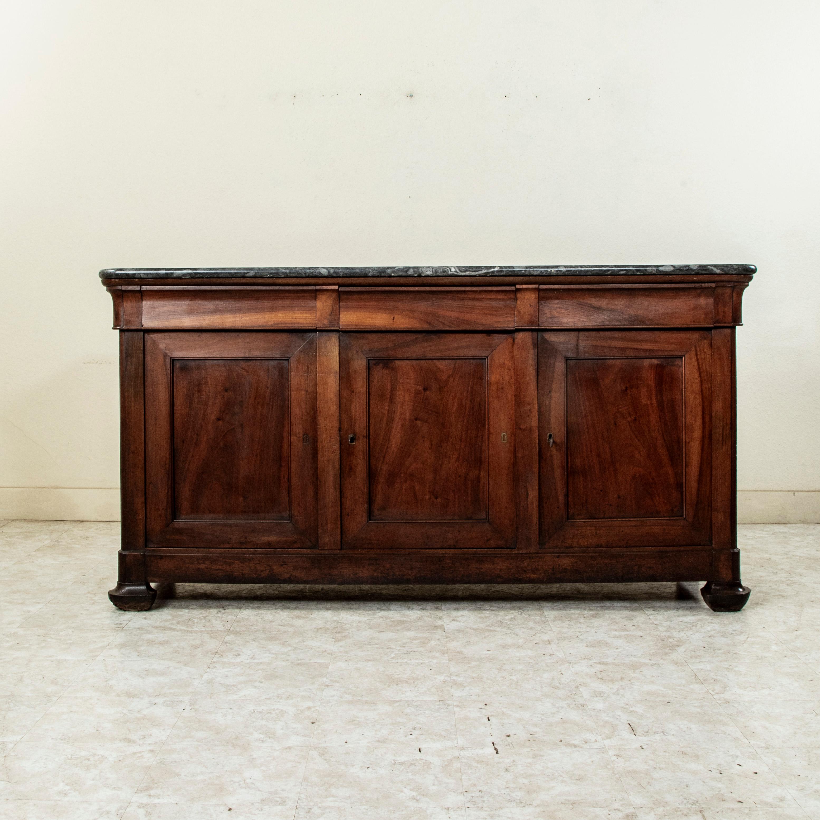 Questa enfilade o credenza francese di epoca Louis Philippe della metà del XIX secolo è costruita in noce massiccio e presenta un piano in marmo. Tre cassetti a coda di rondine si inseriscono perfettamente nel grembiule. Sotto ci sono tre ante che