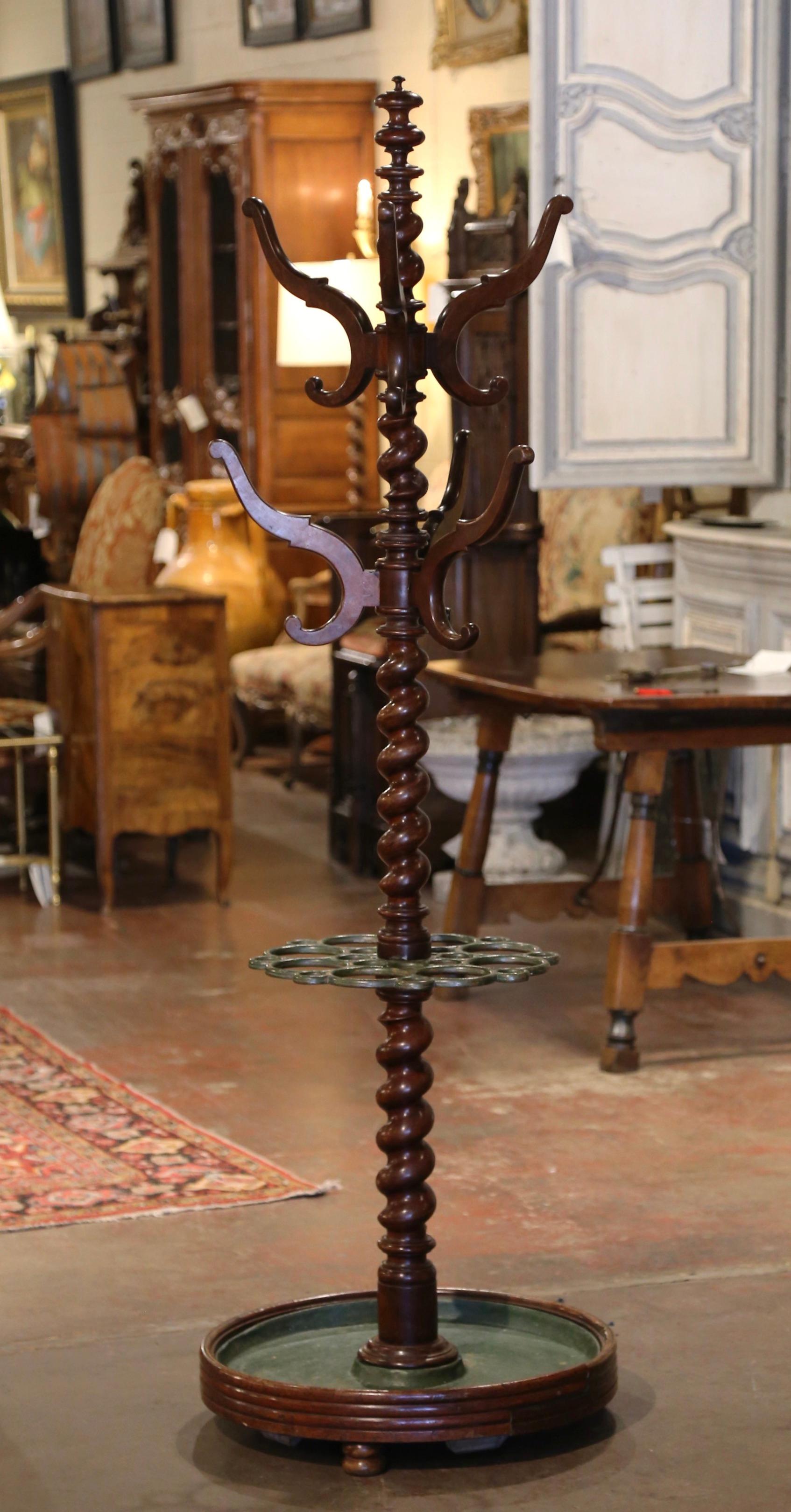 This antique carved fruit wood hall tree was crafted in France, circa 1850. Standing on a circular base ending with bun feet, and dressed with a painted iron droplet tray, the tall rack features a barley twist spiral central stem decorated in the