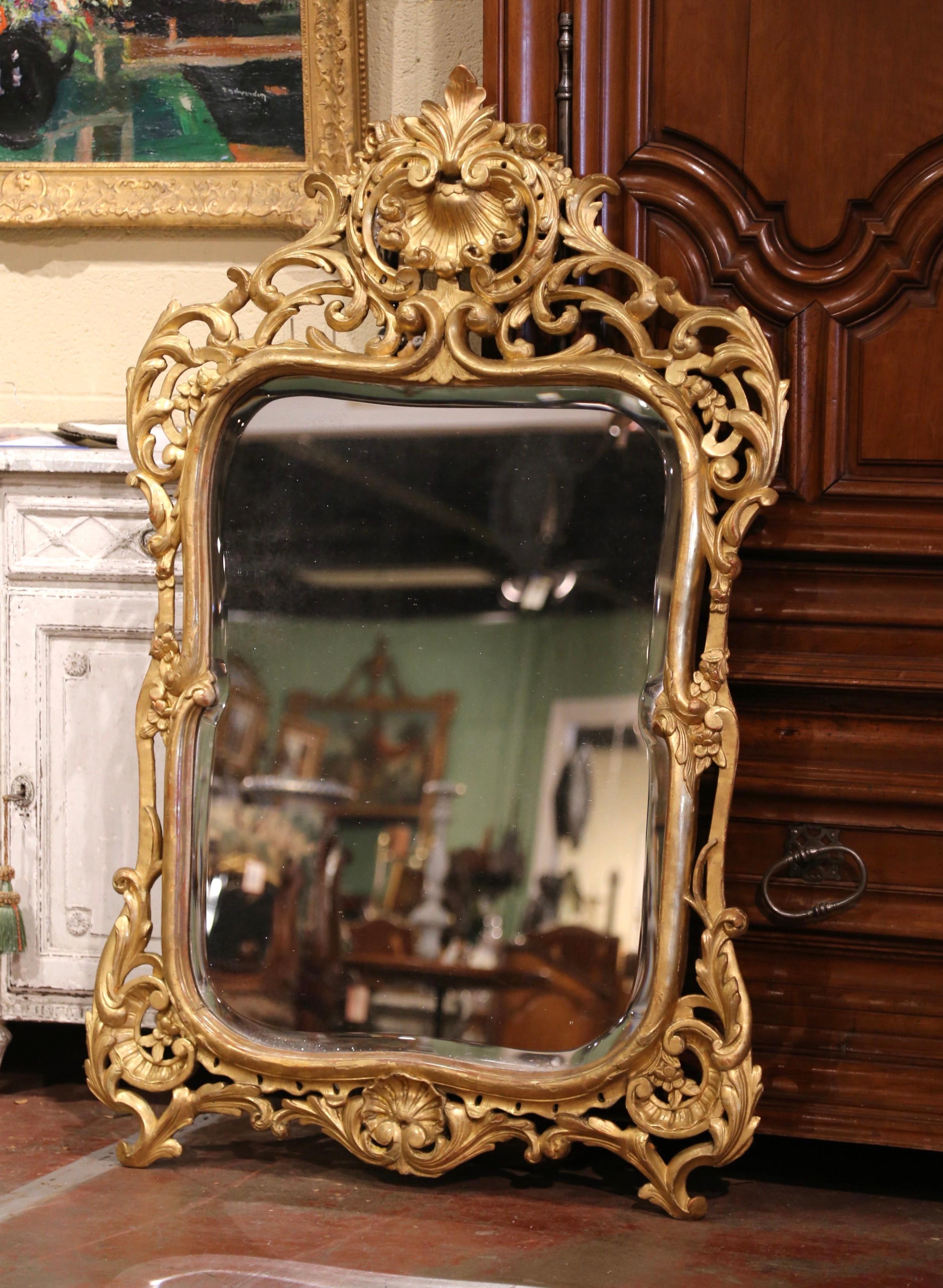 This elegant antique wall gilt mirror was crafted in Southern France, circa 1860. The rectangular mirror features a nicely carved pierced rocaille cartouche at the pediment with delicate scroll, leaf and shell motif. Both sides are embellished with