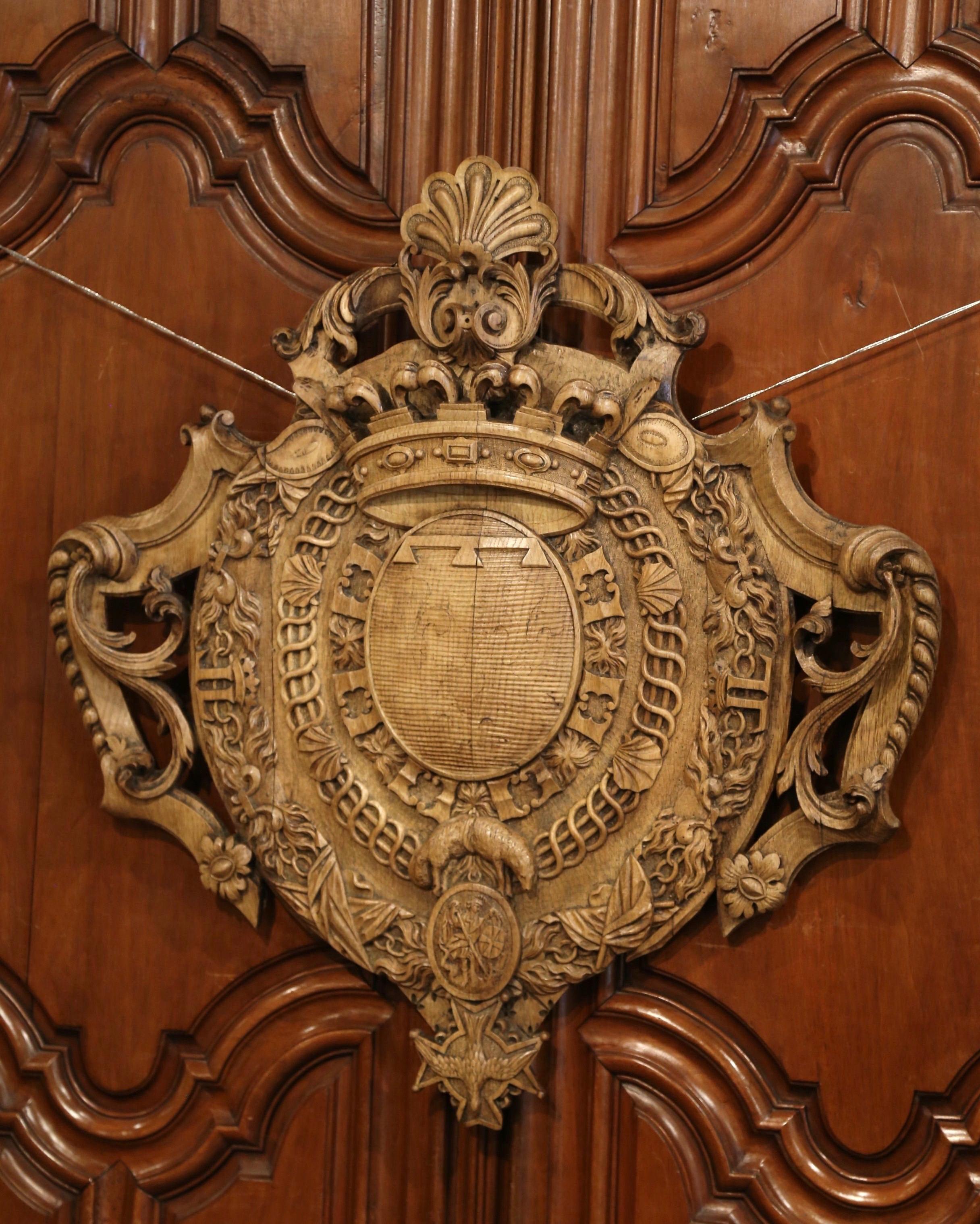 This beautiful, antique crest was crafted in southwest France, circa 1850. The large coat of arms is heavily carved with a shell motif cartouche at the pediment supporting a crown. Both sides feature intricate carvings including scroll decor with