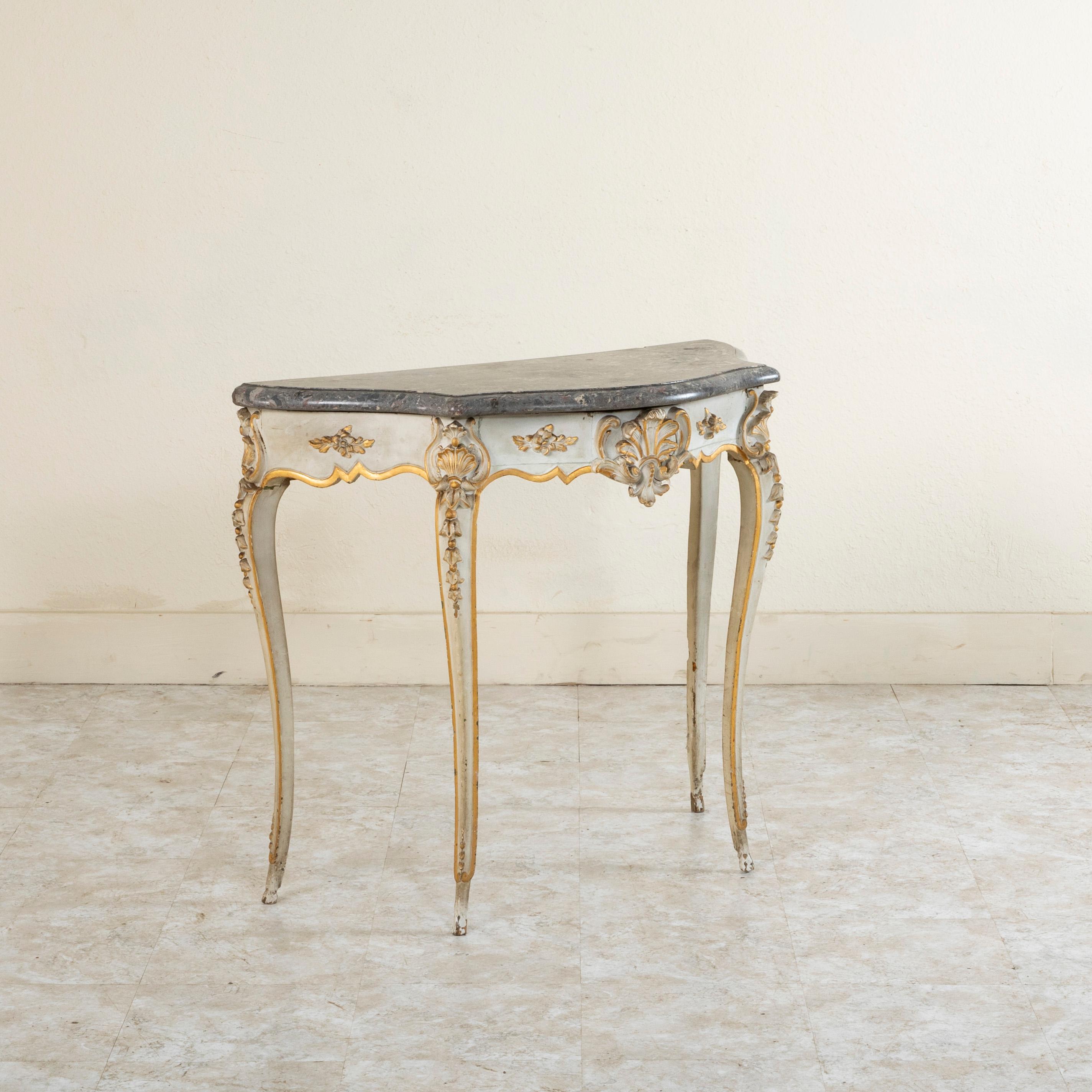 This mid nineteenth century French Louis XV style painted console table features a beveled marble top. Painted in a greyish white with gold accents, this console is detailed with a central hand carved shell flanked by gadrooning leaves. The shell