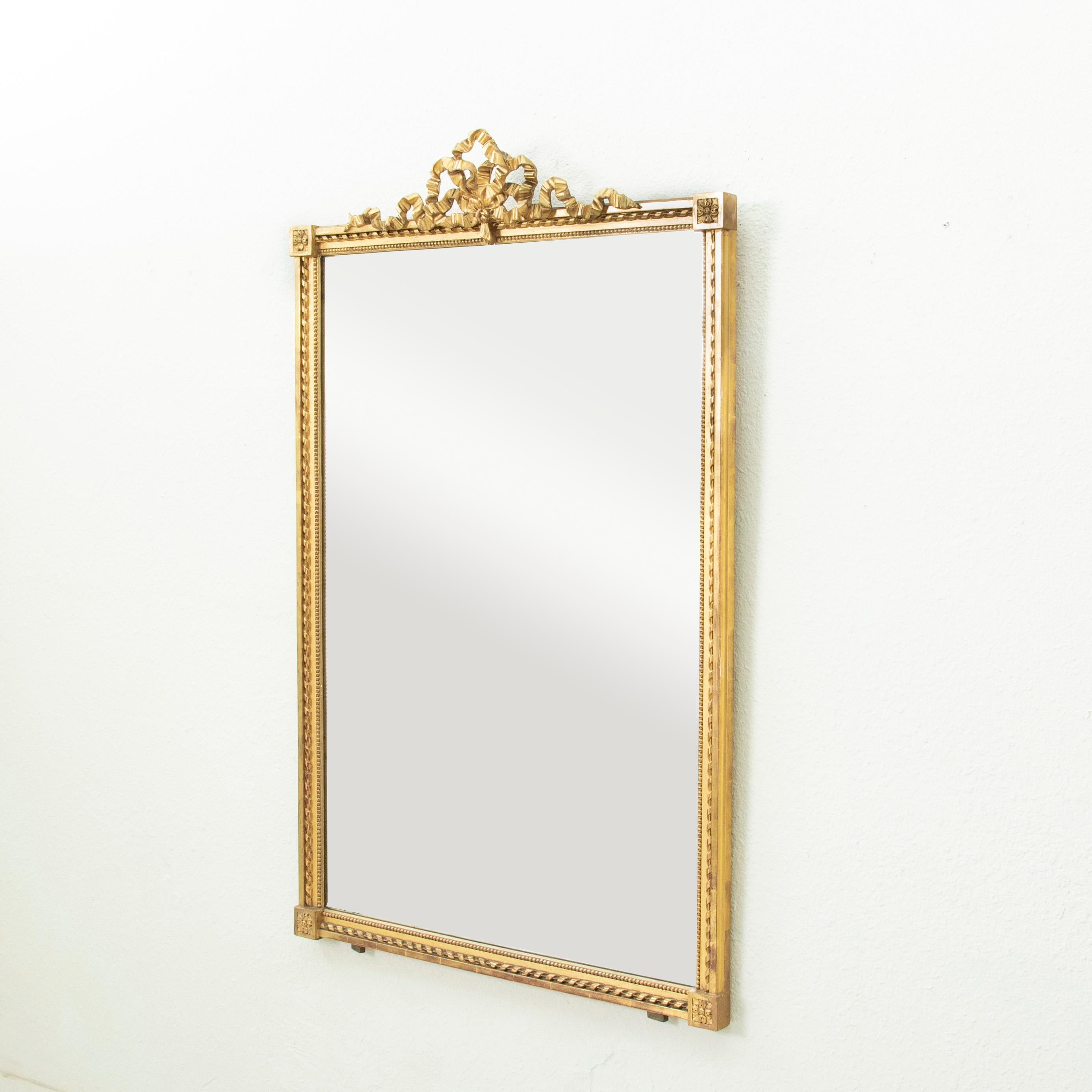 Diese Mitte des neunzehnten Jahrhunderts Französisch Louis XVI-Stil vergoldetem Holz Spiegel verfügt über eine klassische geknotete Band auf der Krone. Der 56,5 cm hohe Rahmen ist mit Louis-XVI-Motiven wie gedrehten Bändern, Perlen und Eckrosetten