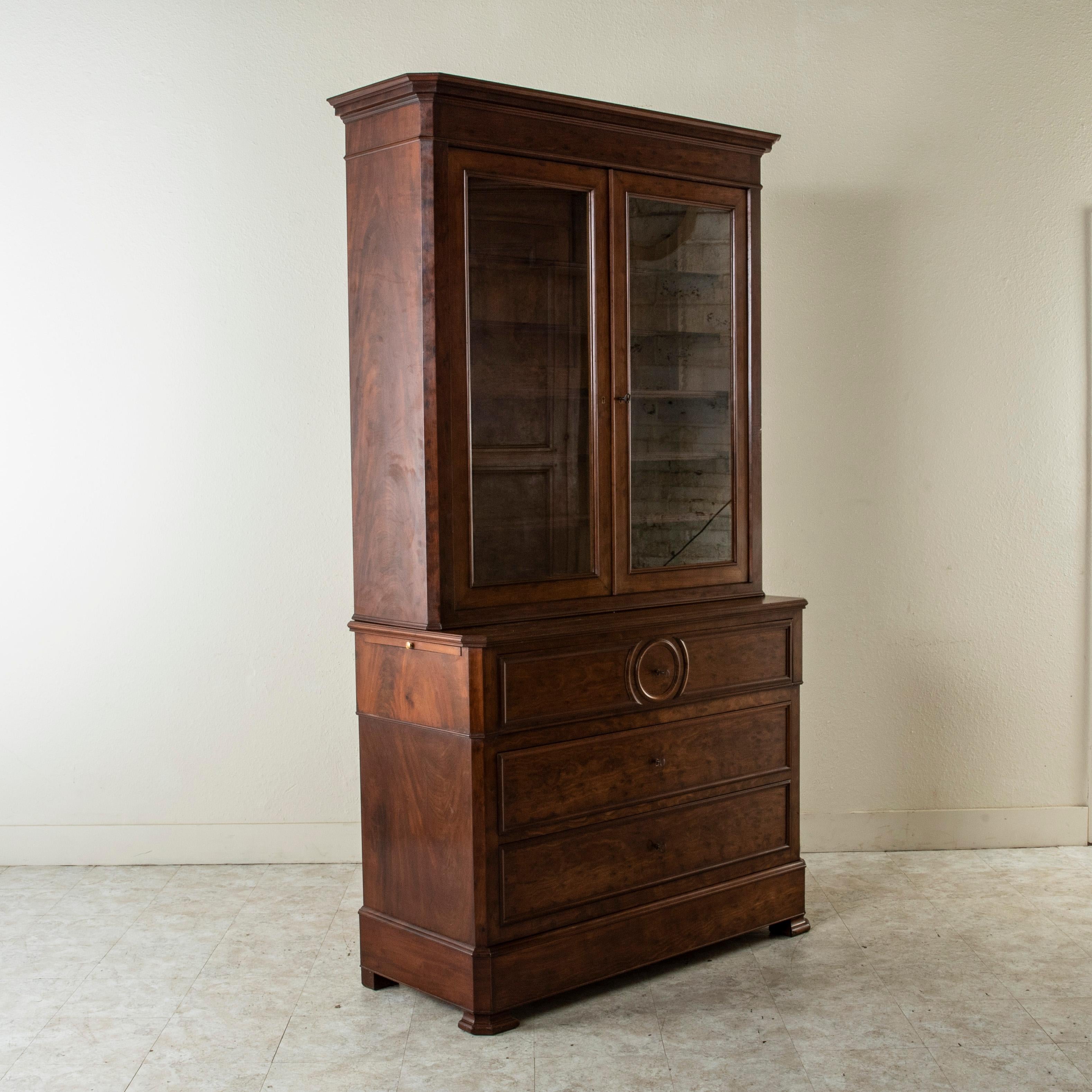 This nineteenth century French Napoleon III period buffet deux corps or bookcase is constructed of mahogany and features clean simple lines. Its upper cabinet is fitted with glass doors and contains five adjustable interior shelves. The lower