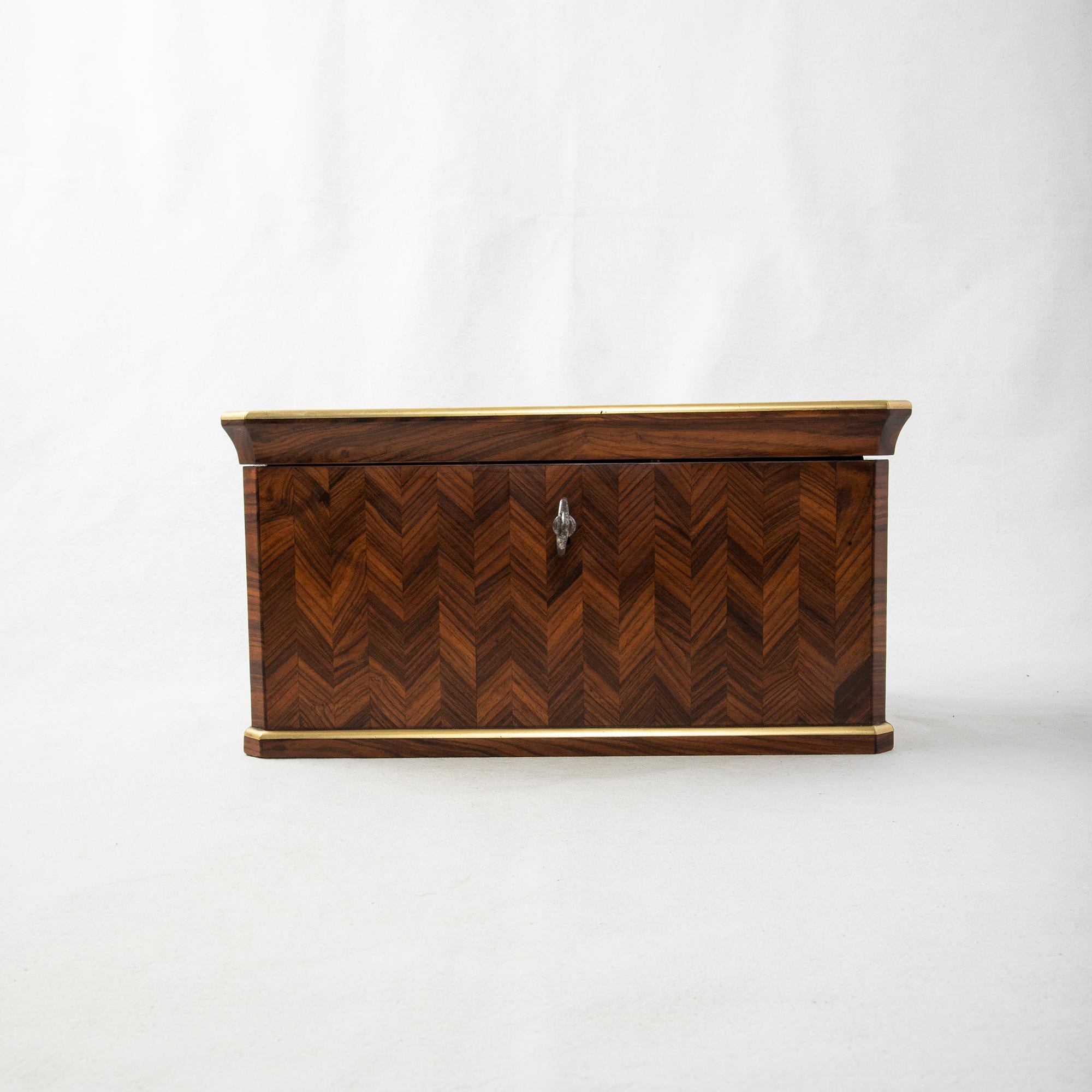 This mid-nineteenth century Napoleon III period tea box or tea caddy features marquetry of palisander in an inlaid chevron pattern. Bronze edging around the top and base outer edges lend strength as well as protection to the fine wood. The interior