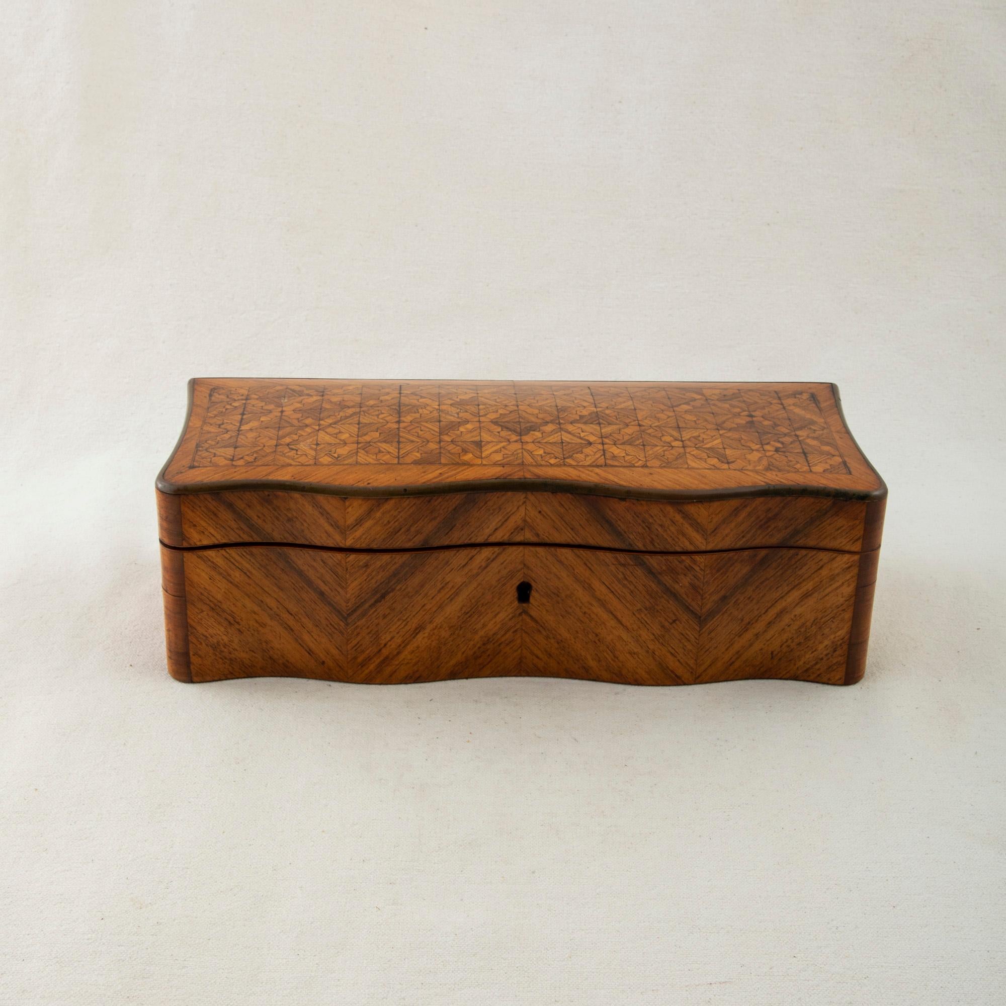 This mid-nineteenth century French Napoleon III period glove box is made of rosewood and features a curved front and an intricate geometric diamond pattern inlaid into the top. The sides display a chevron pattern. It is accented with a bronze band