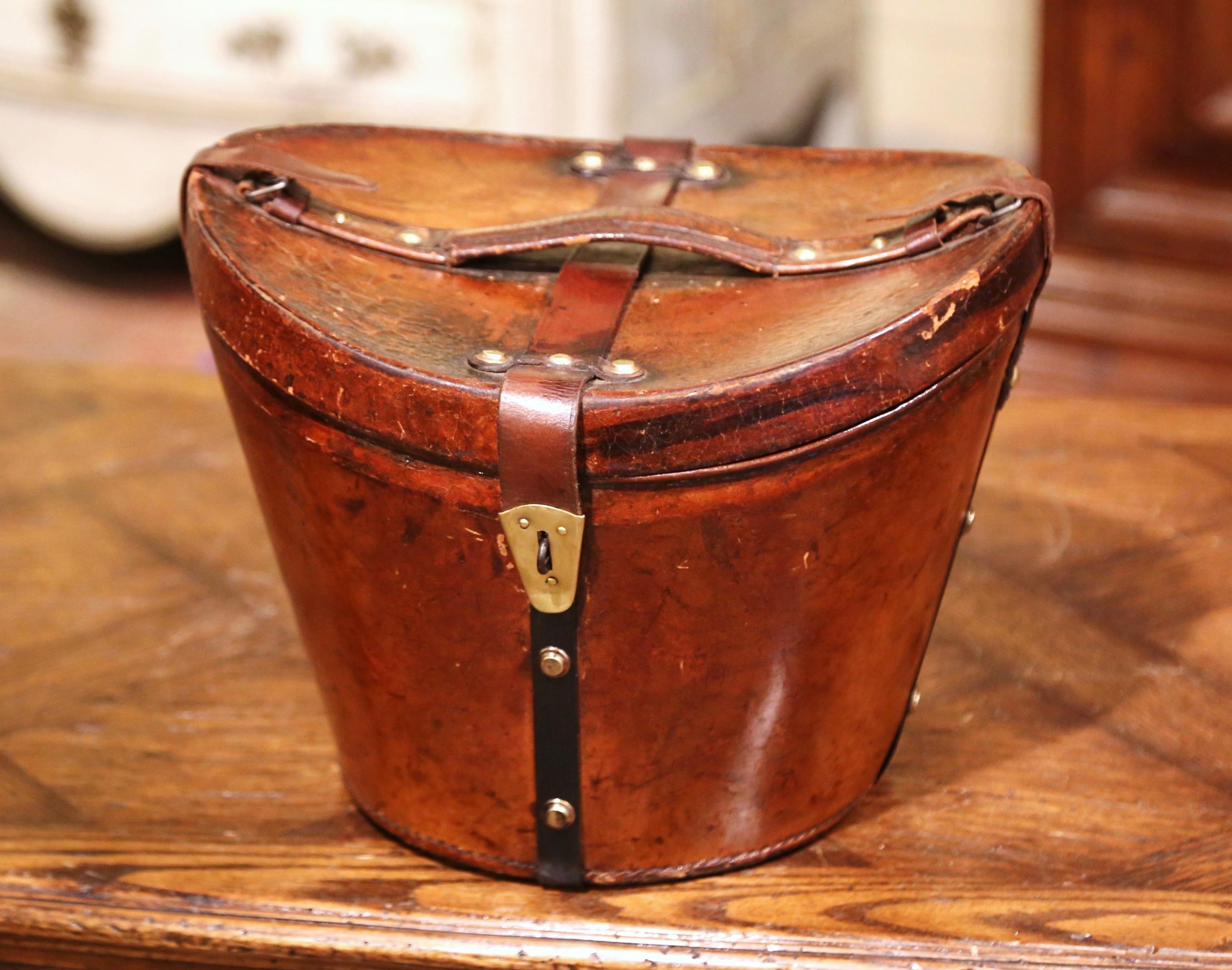 This exquisite, antique pigskin hat box was crafted in France, circa 1870. This leather high box features leather straps and handle embellished with decorative brass nail heads, and the inside is dressed with the original red velvet upholstery. The