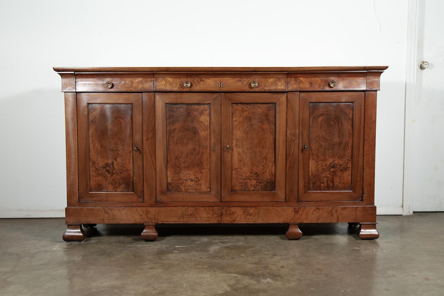 A very handsome mid-19th century French period Louis Philippe enfilade buffet handcrafted of solid chestnut and burled chestnut by skilled artisans near Normandy, having four burled drawers over four doors with burled panels. Burled apron resting on