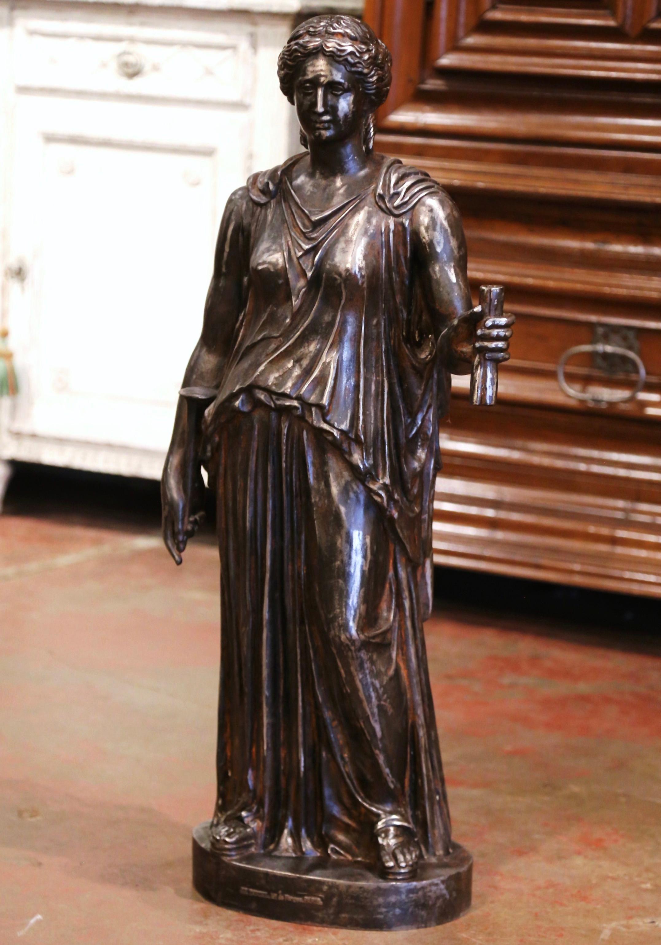 Decorate an entry or a patio with this elegant antique statuary. Crafted in France circa 1850, and made of cast iron, the sculpture depicts a Roman figure in formal clothing holding a torch. The art work is signed on the front base by the artist,