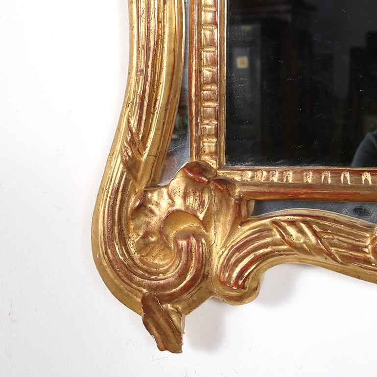 Un elegante specchio da parete finemente intagliato in stile Regency proveniente dalla Francia. La sua cornice in legno dorato a forma di violino è ancora vivacemente vestita con la foglia d'oro originale e il supporto in legno di listello