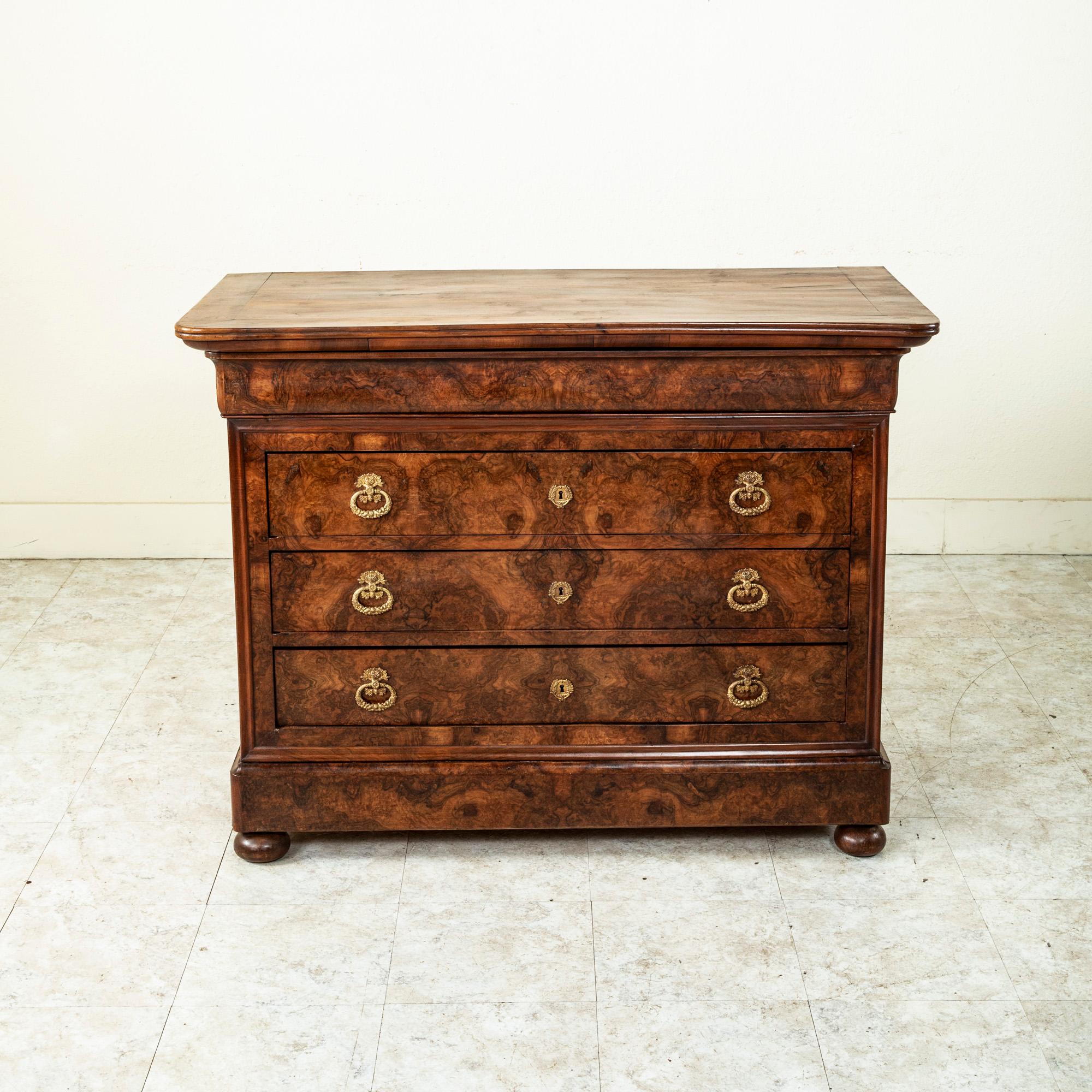This mid-nineteenth century French Restauration period commode or chest of drawers displays exemplary craftsmanship with a facade of book matched burl walnut, solid walnut panel sides, and is finished with a solid wood top. Three lower drawers of