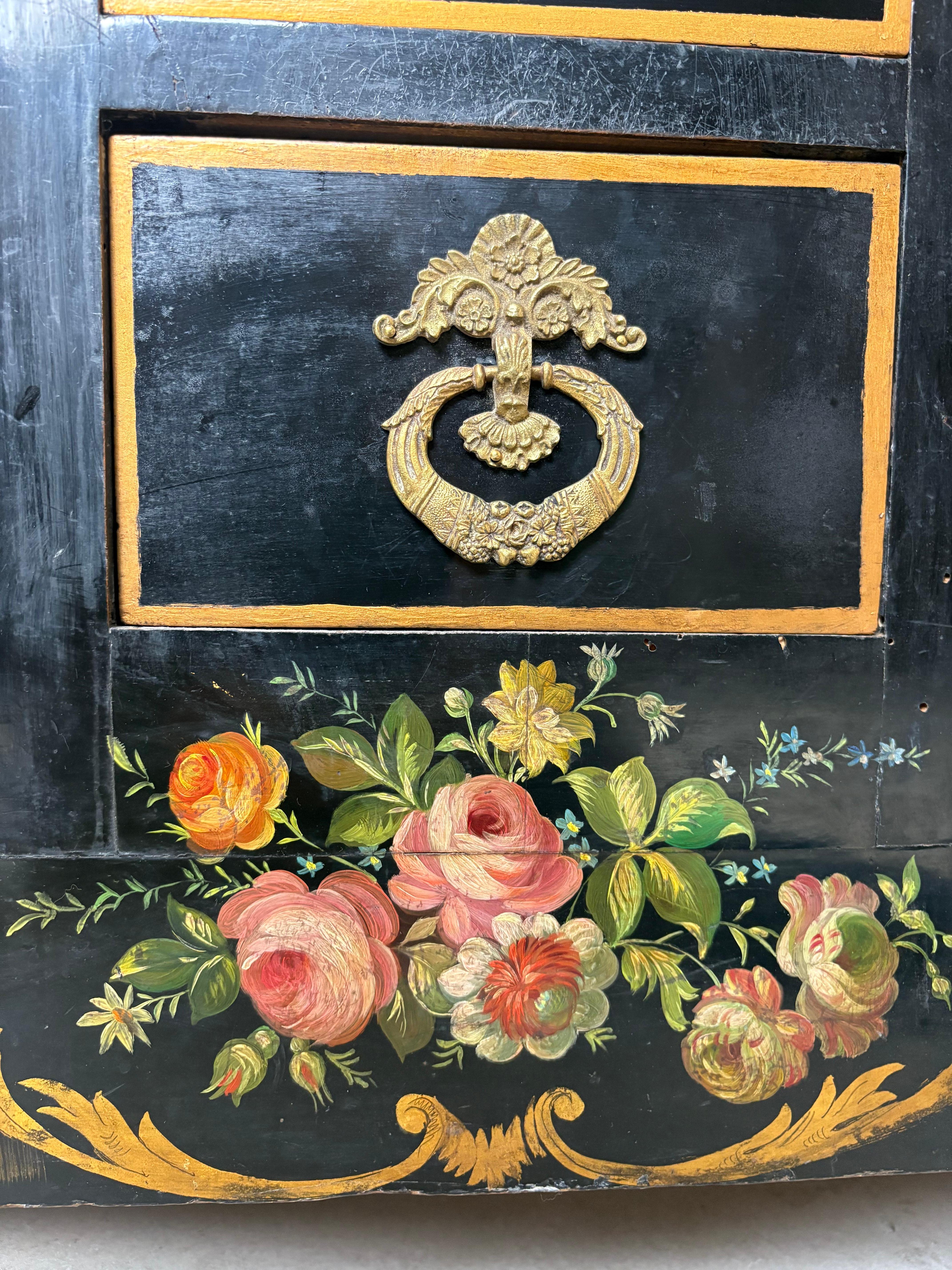 Excepcional mueble auxiliar francés de mediados de siglo con exquisita pintura de flores. Consta de cuatro cajones centrales con tiradores originales de latón inciso flanqueados por un par de armarios con paneles arqueados de urnas pintadas, follaje