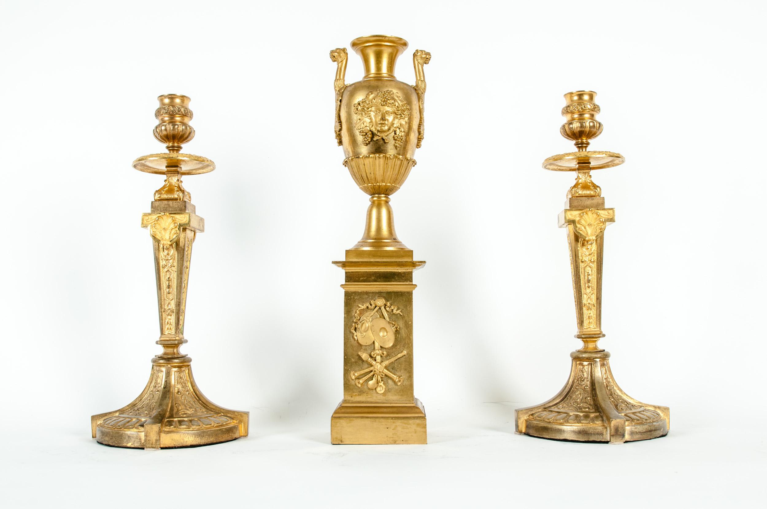 Mid-19th century gilt bronze three-piece garniture set. Set include pair candlestick and urn. Each piece is in great antique condition. Minor wear consistent with age / use. The candle stick is about 12.7 inches high x 5.3 inches base diameter. The