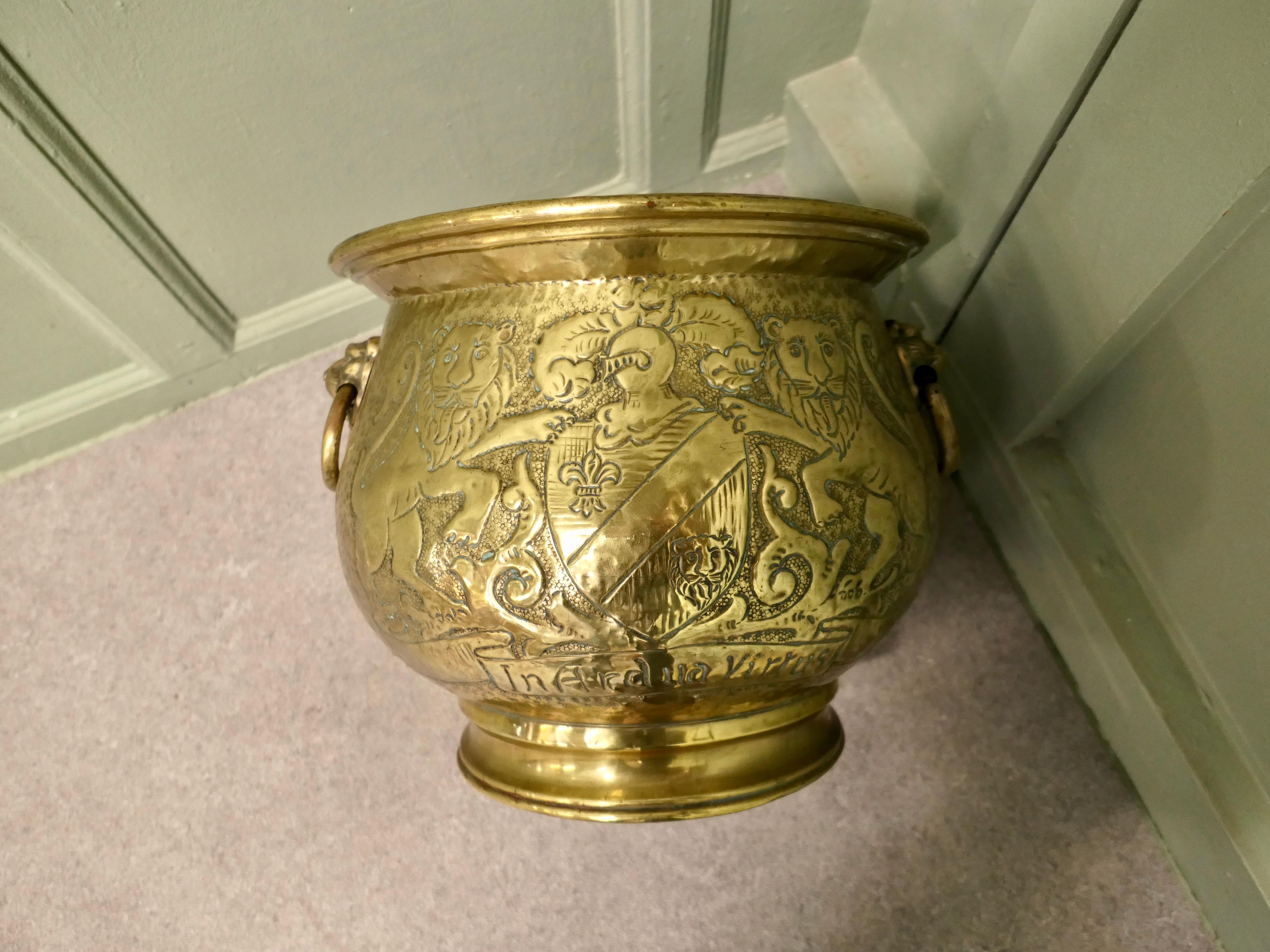 19th Century Gothic Brass Jardiniere with Shields 

This is a very old piece it is decorated with Lions and Shields and it has a Latin Motto inscribed on both sides which means ‘Virtue in Difficult Times’
The pot is hand made with lion’s mask
