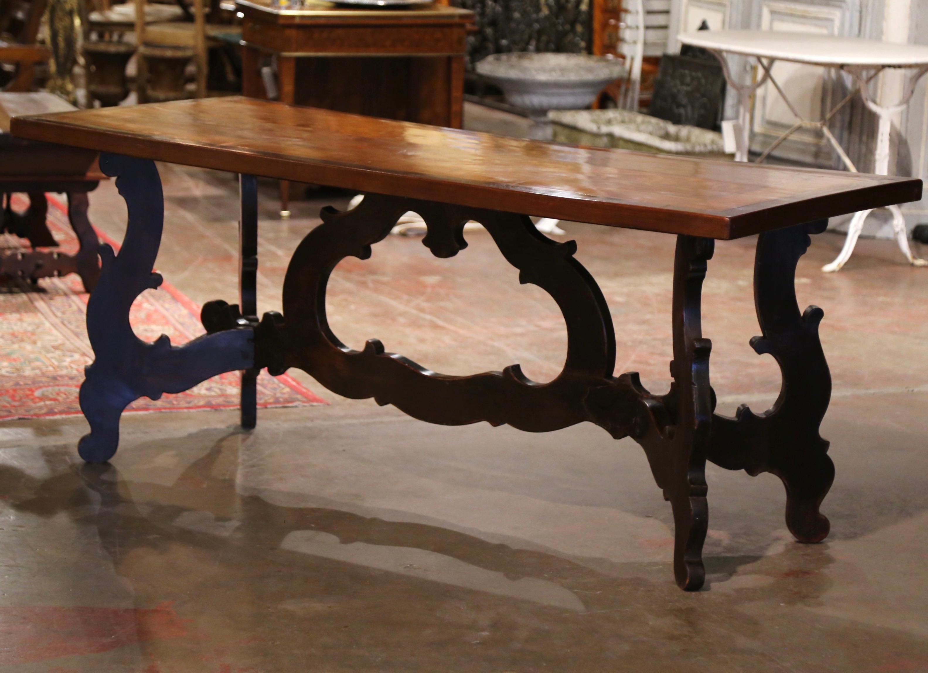 This elegant, antique fruit wood dining room table was crafted in Italy, circa 1830. The intricate table features a solid top made from a single walnut plank and embellished with scrolling foliate marquetry and a decorative inlay cherry band around
