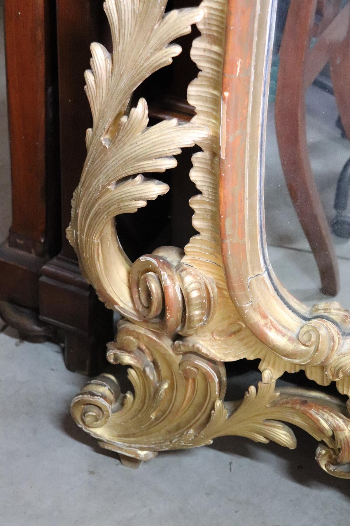 Beautiful elegant large wall mirror in perfect Baroque style, 1850s wood hand carved with finely and richly swirls and curls. Refinement decorated in gold leaf. In good antique conditions.