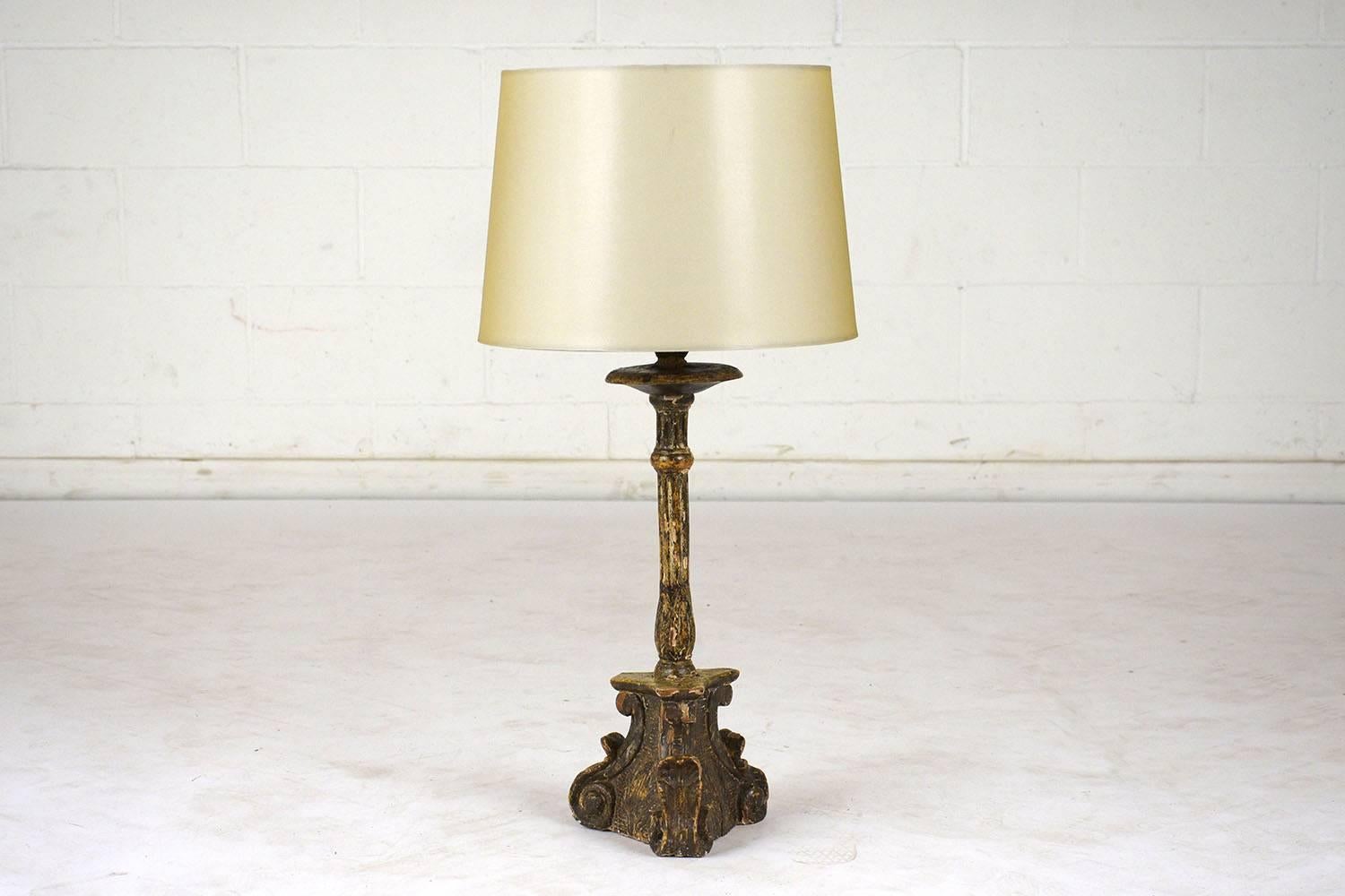 This 1850s Italian Baroque-style table lamp features a base made of carved wood with a multi-color polychrome finish. The base of the lamp is adorned with carved cherub faces, scrolls, and acanthus leaves. Accompanying the lamp is a new sand color