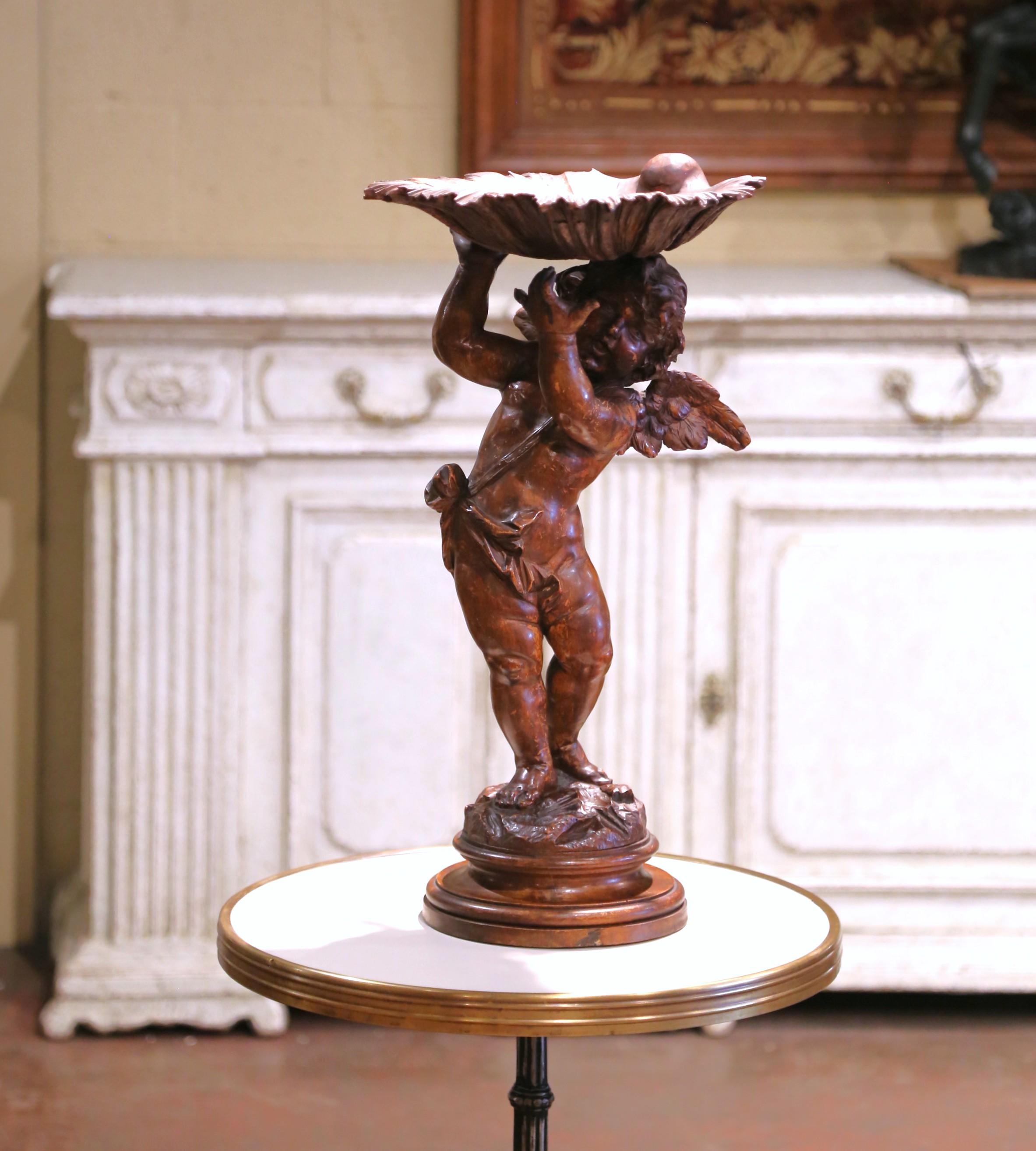 Tallada en Italia hacia 1870, esta compota figurada del siglo XIX, finamente detallada, presenta un juguetón querubín alado que sostiene sobre su cabeza una amplia jofaina lobulada. Esculpido en nogal macizo, el putto está descalzo sobre una base