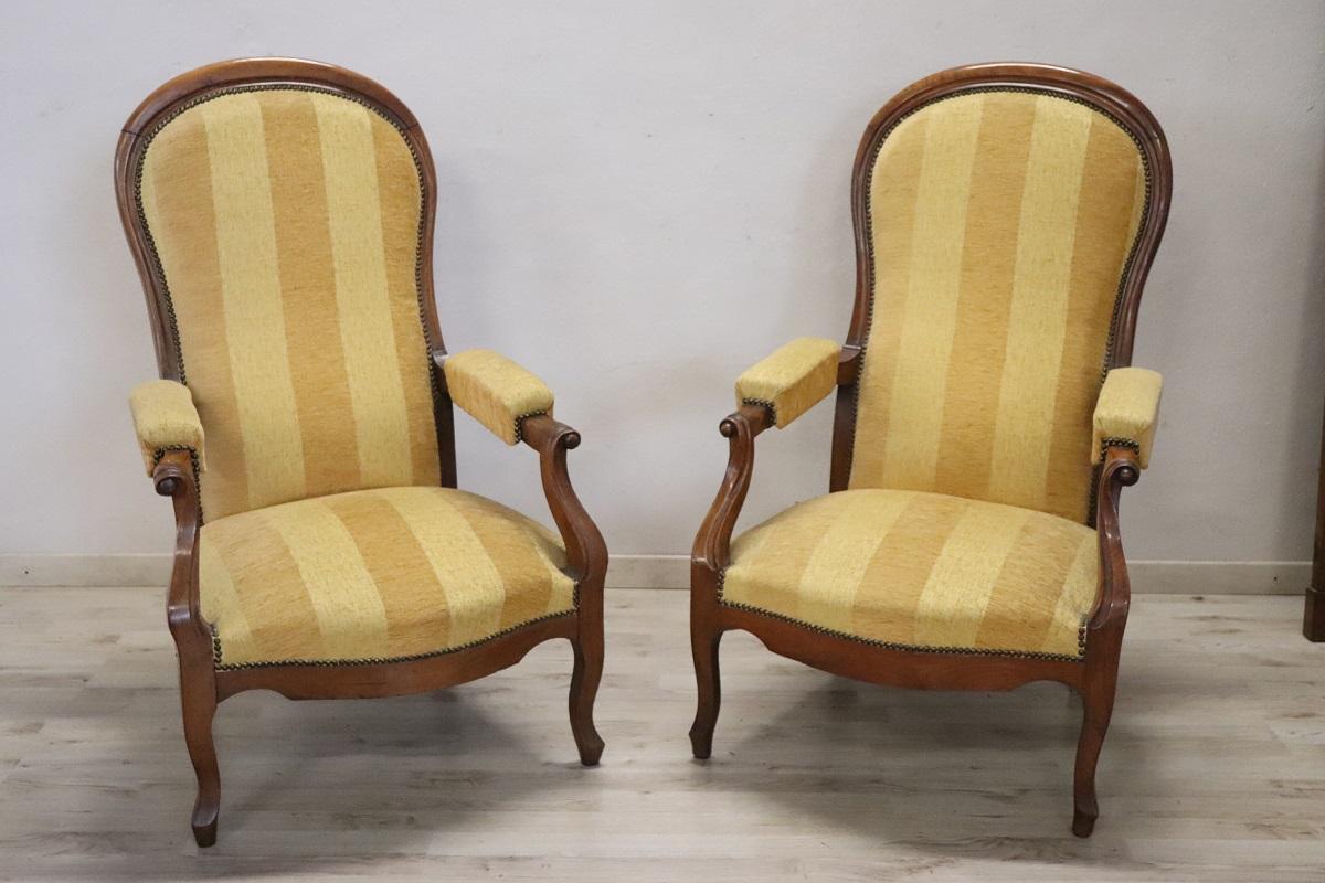 We present this splendid pair of antique Italian upholstered armchairs, made in the mid-19th century during the Louis Philippe period. The structure is made of fine walnut wood while the seats and backrests are padded for greater comfort and covered