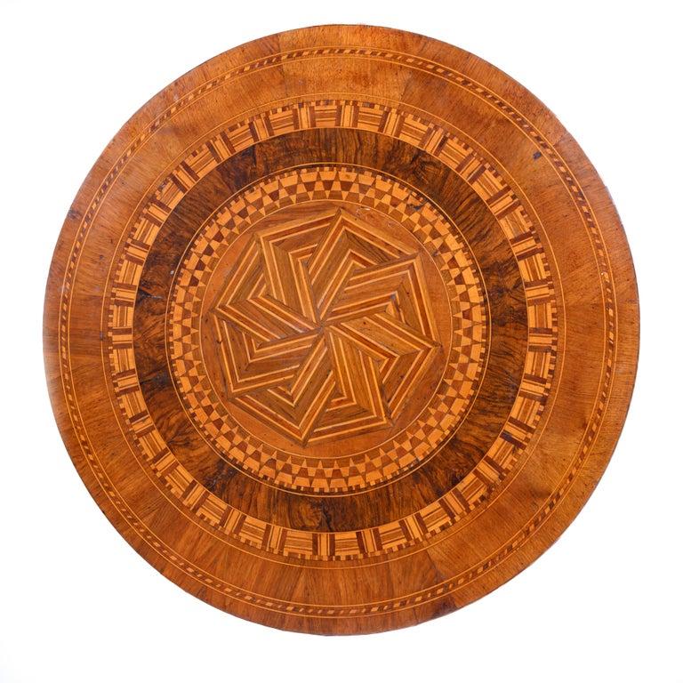 Circular marquetry inlaid top raised on a baluster turned support resting on a tripod base with slightly curled feet. This Italian round walnut veneered center tabletop is decorated with parquetry, thin layers of walnut, maple, box, mahogany, cherry