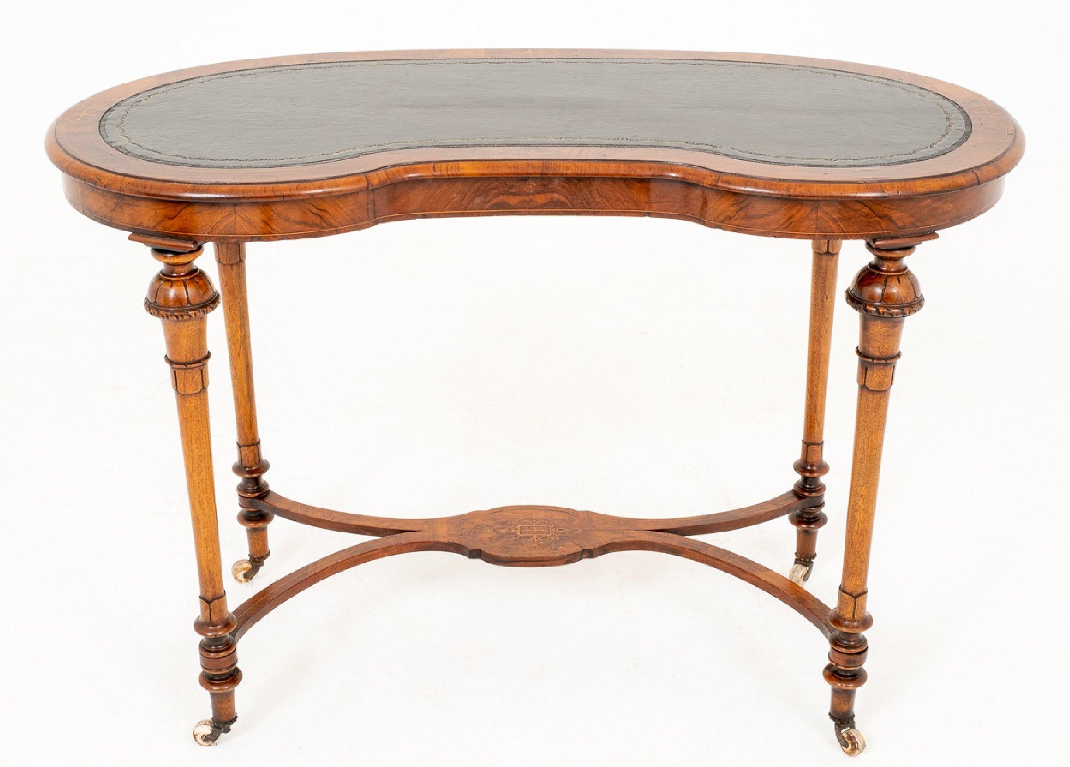 This mid-19th century ladies walnut writing table features beautifully carved and turned cabriole legs on porcelain castors with a shaped stretcher base. The kidney shaped top has an inset tooled leather top with inlay detail around the top edge. It