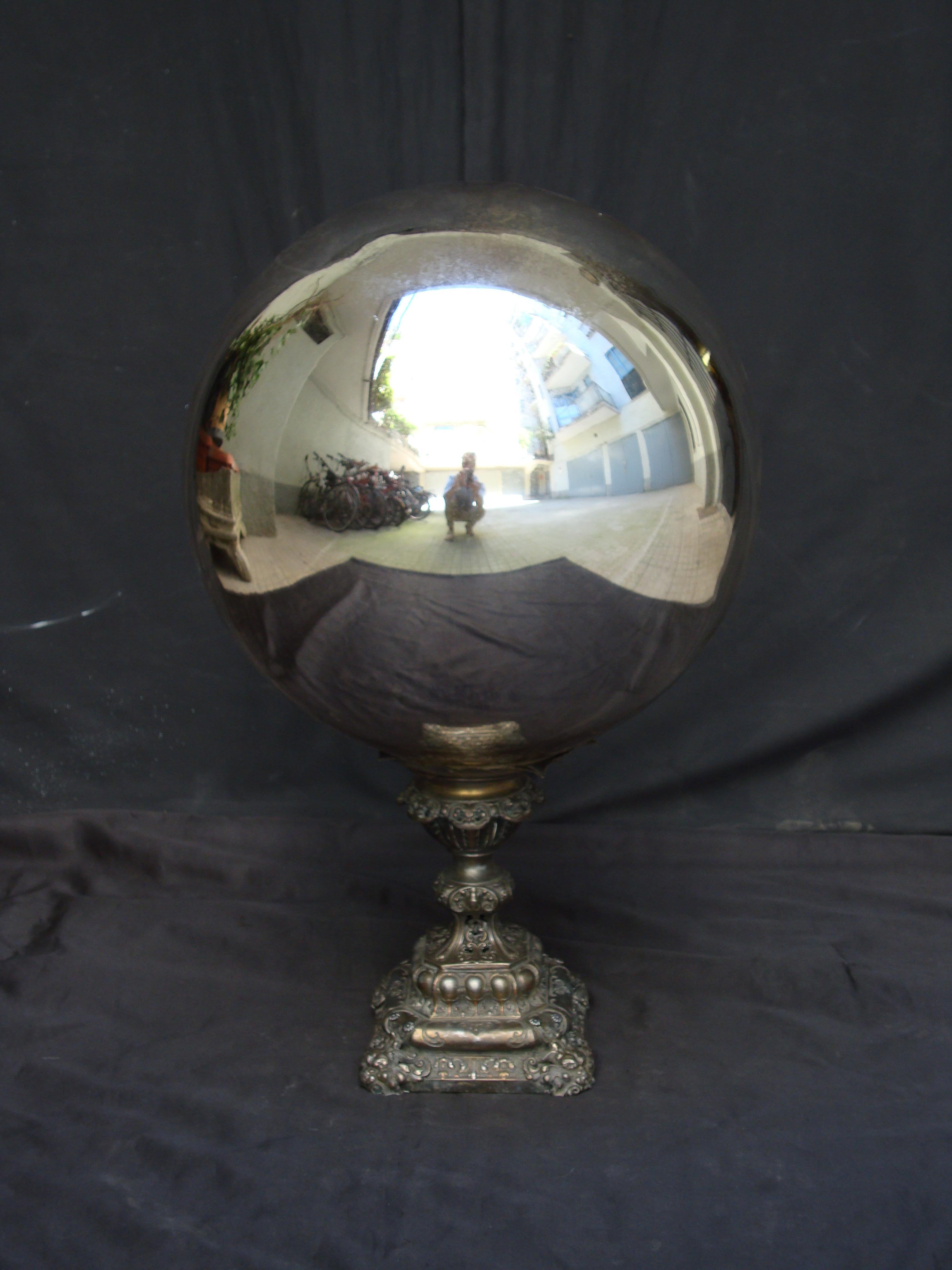 A mid-19th century large mercury glass witch ball, on a metal base with anthropomorphic details.