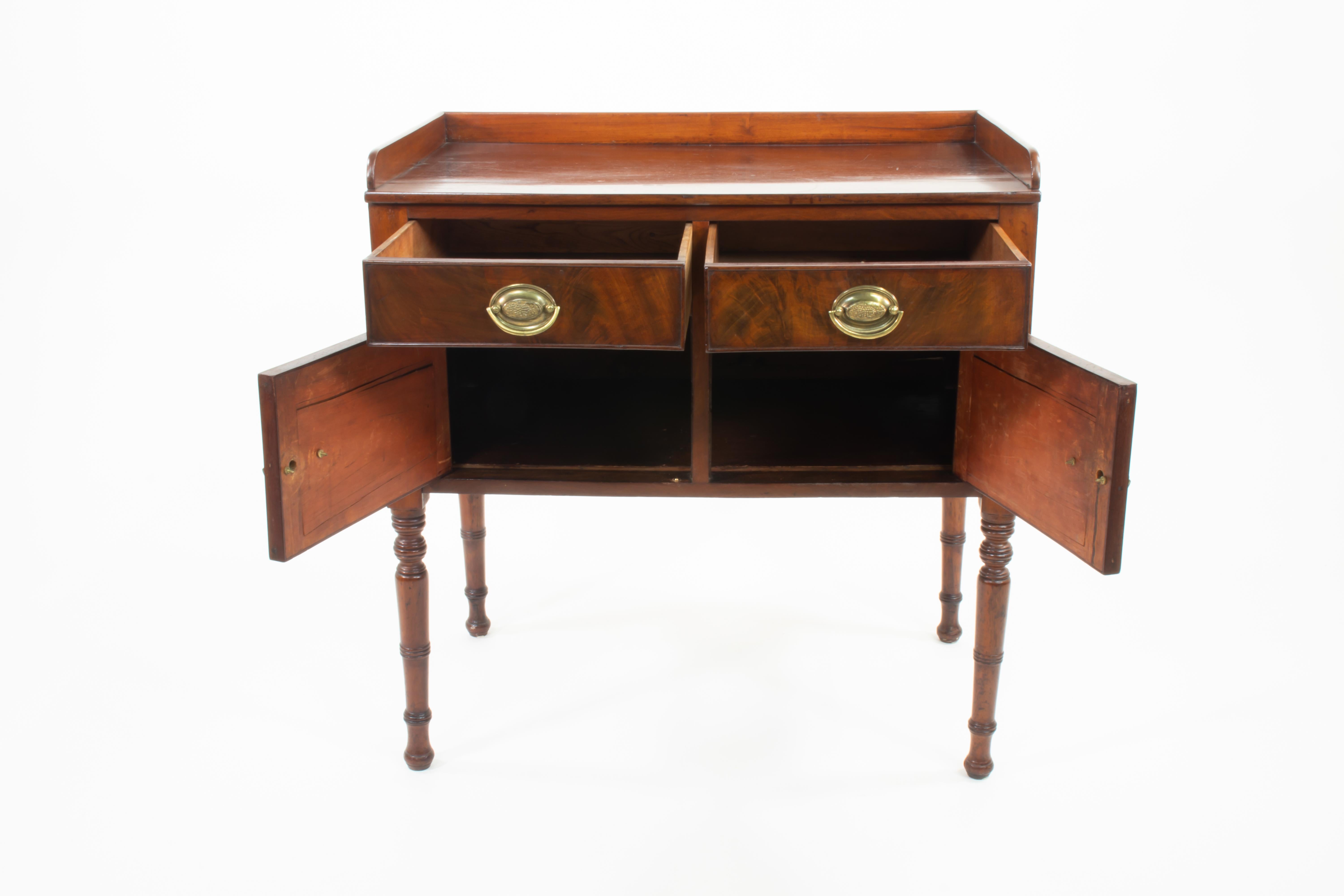 Un raffinato mobile da camera in mogano a fiamma della tarda Reggenza, inglese, 1865 circa, con due cassetti corti sopra un armadio a due ante, sollevato su eleganti gambe tornite. Realizzato in mogano a fiamma riccamente figurato con una superficie
