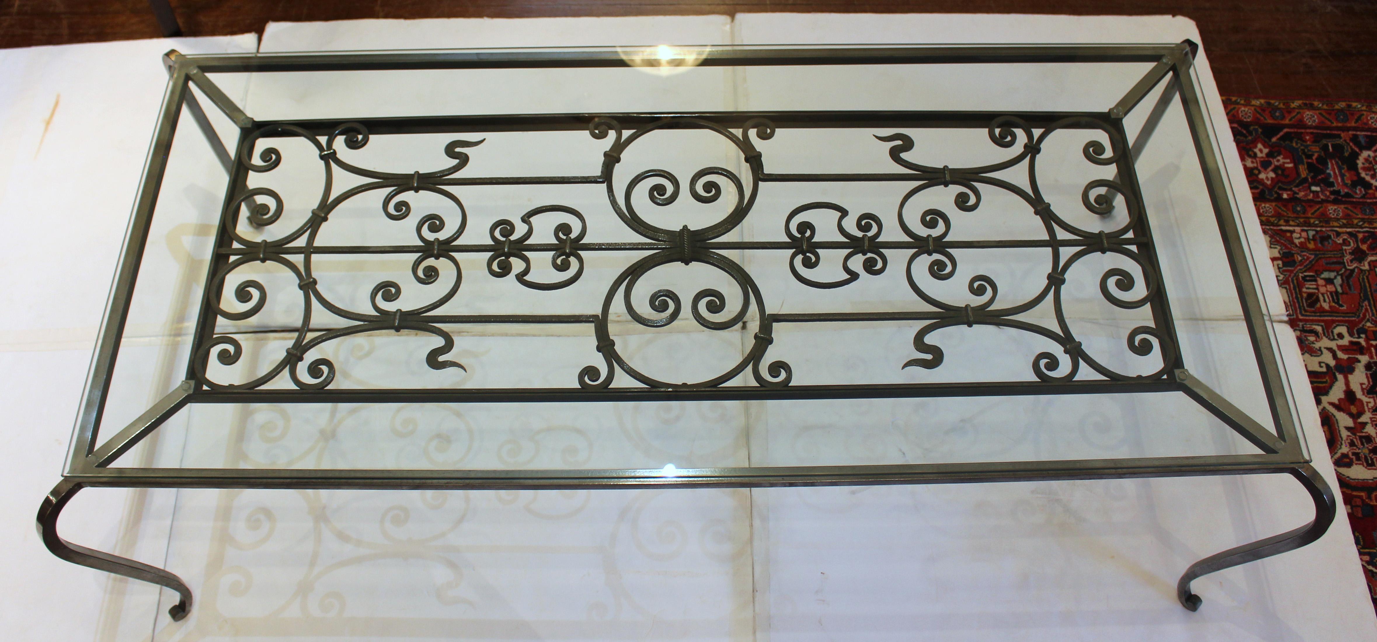 Table basse en verre et acier français poli du milieu du 19e siècle et plus tard. Créée autour d'un panneau de fer ancien, les motifs de volutes sont accentués par des pieds gracieusement enroulés. Plateau en verre : 63,5