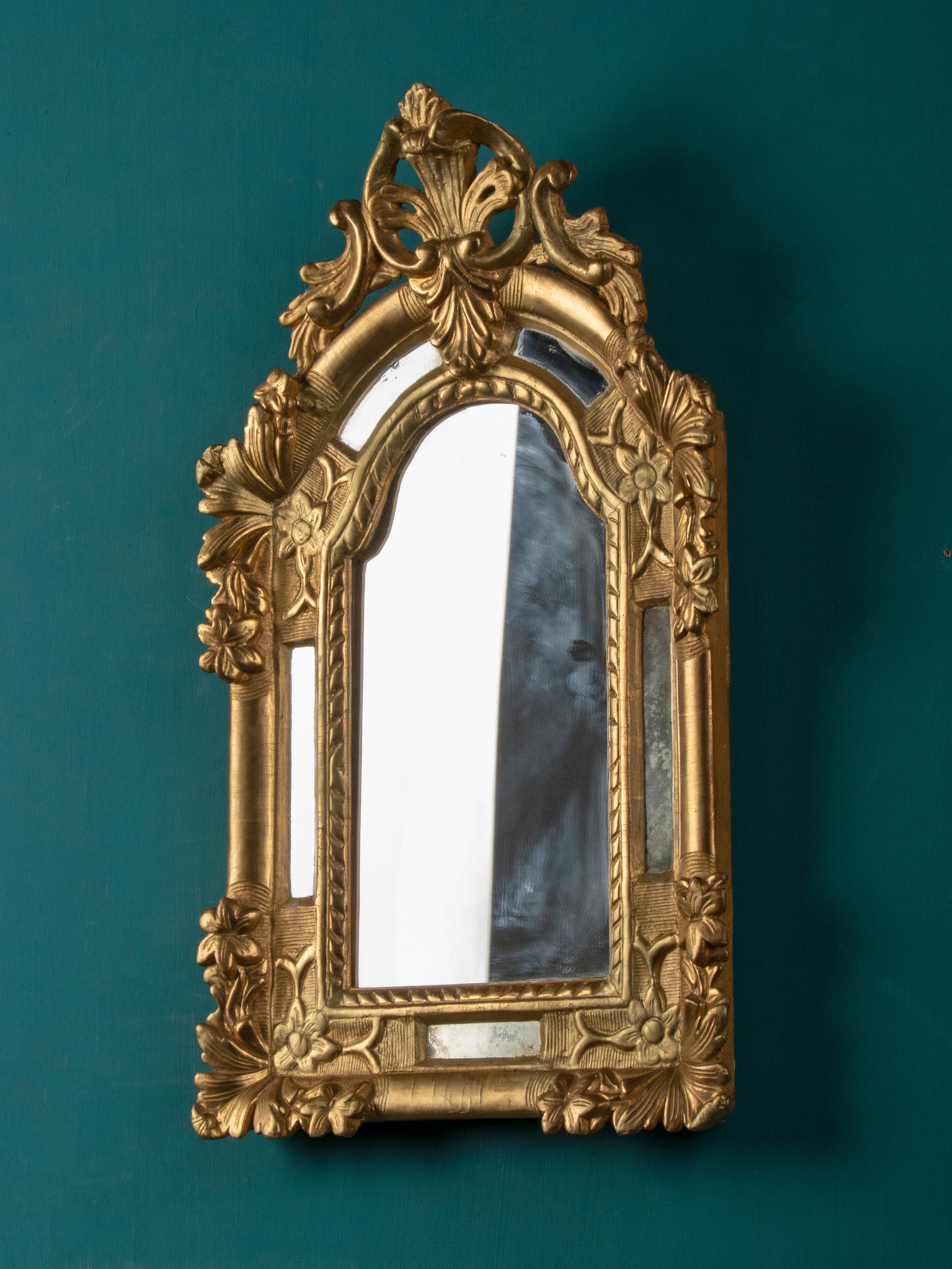 A small and elegant Louis XV Style French Wall mirror with floral decor. The mirror is made of carved wood. It has small mirror glasses on the sides. This model is also called 