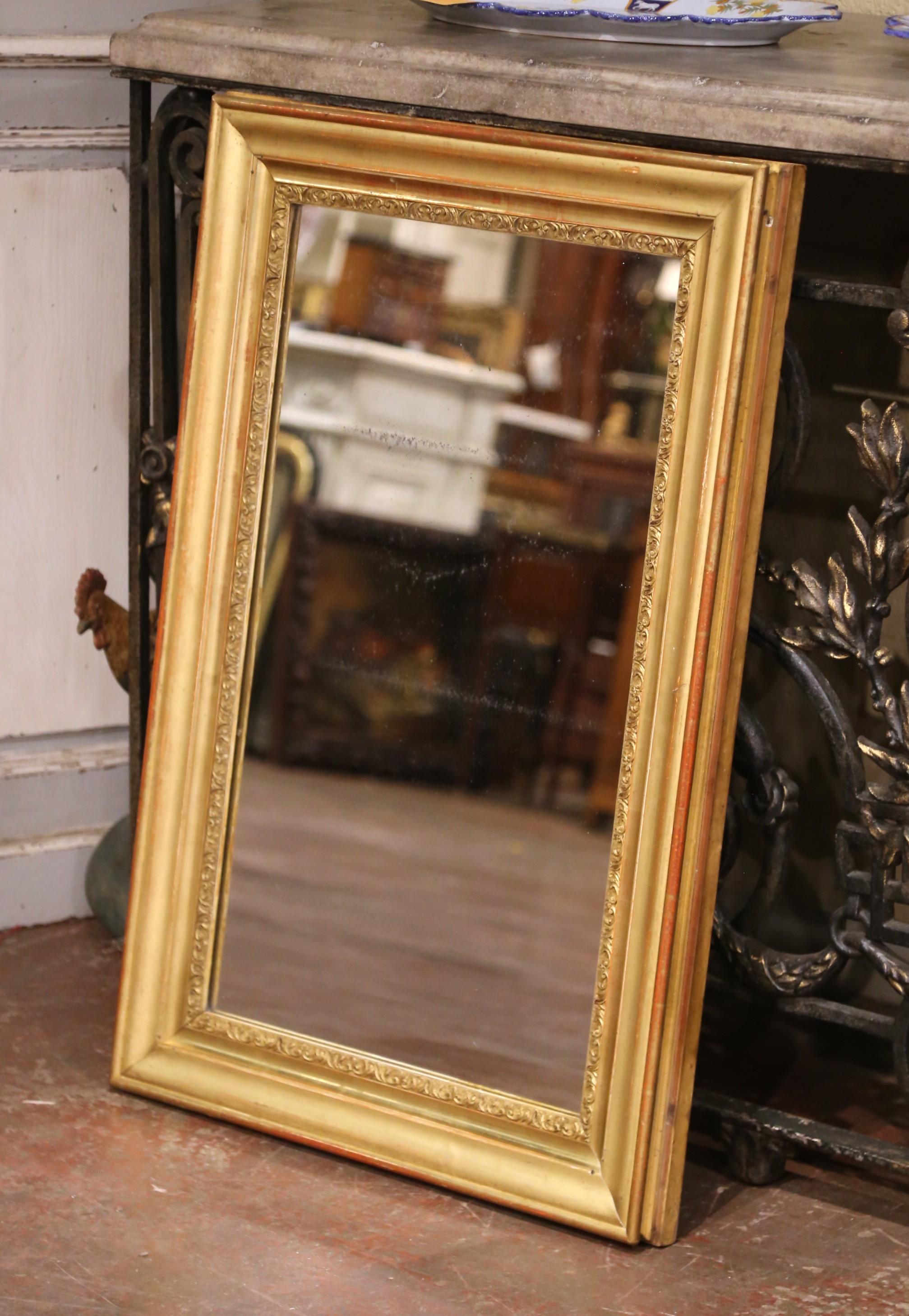Elegant and refined, this antique Louis XVI-style mirror was crafted in France circa 1860. The rectangular frame is carved from solid wood and finished in hand-applied gilt, featuring a simple stepped profile with a delicate band of foliate motifs