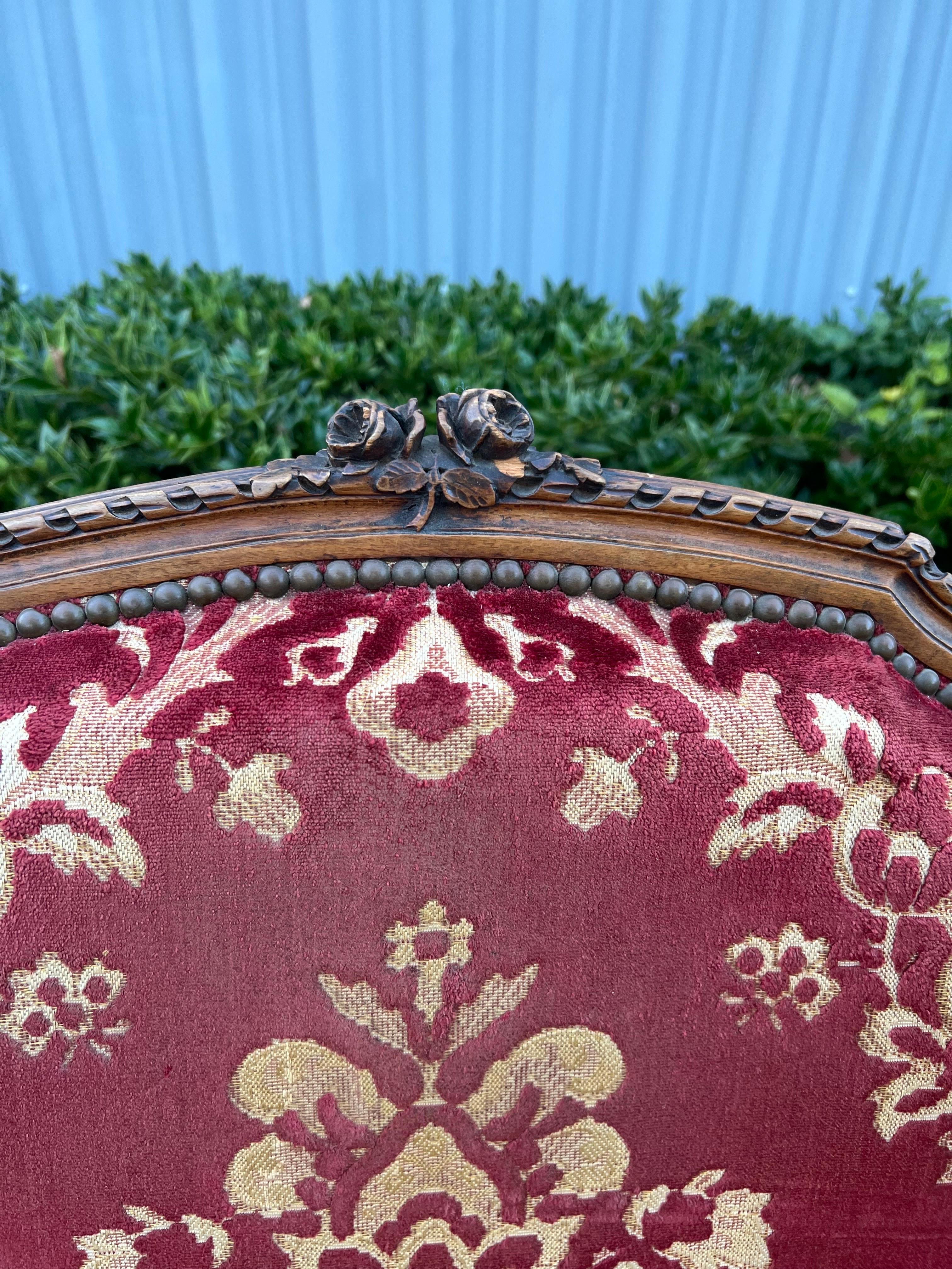 Antique highly carved and detailed Louis XVI FIRESIDE  wingback chair which has been previously reupholstered in a Vintage red cut velvet damask.