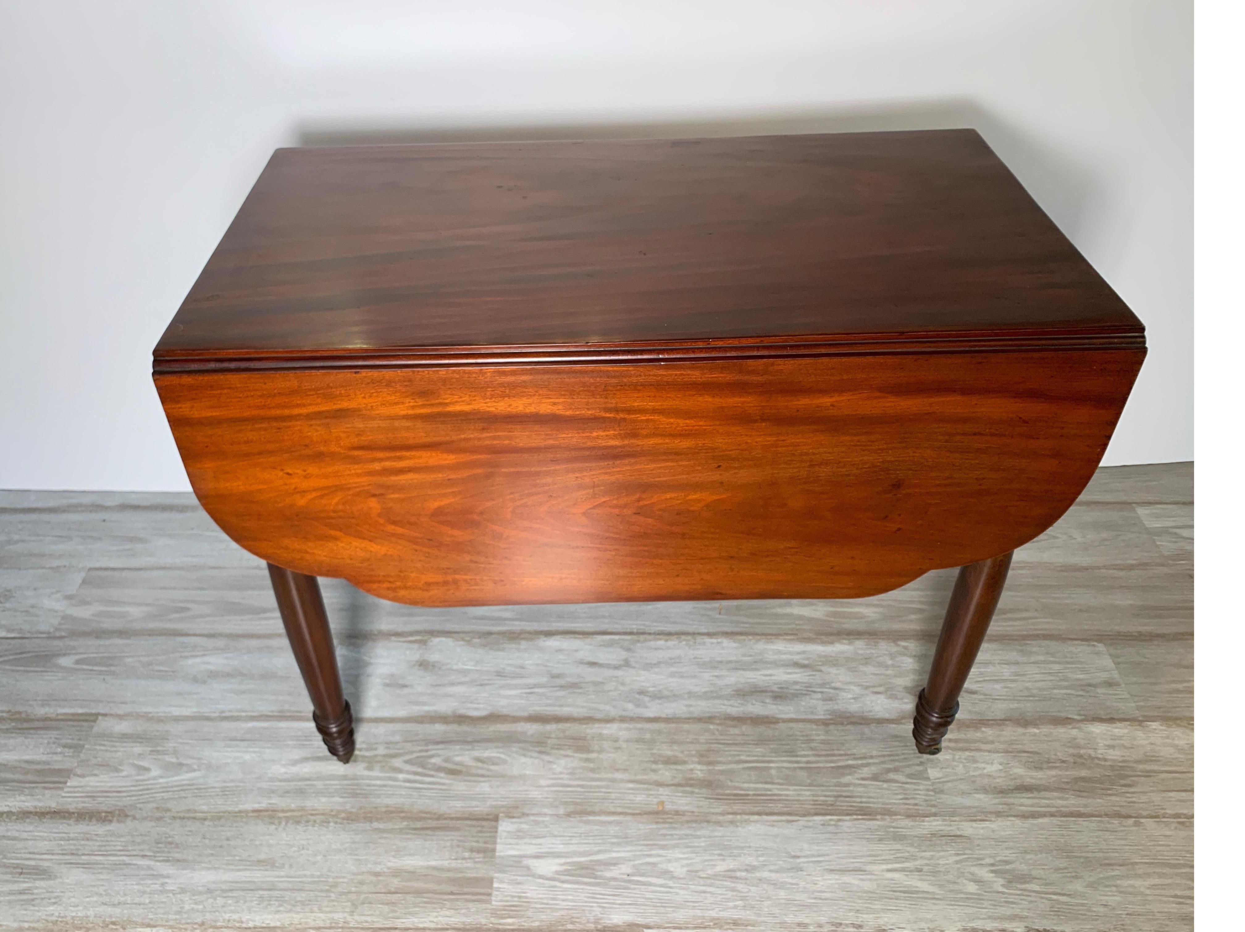 Antique medium sized solid mahogany drop-leaf table with hand-turned legs. The table with two scalloped leaves which open to 46 inches when closed 20.5 inches, 36 inches deep. Original finish showing age lightening but with a recent polish.