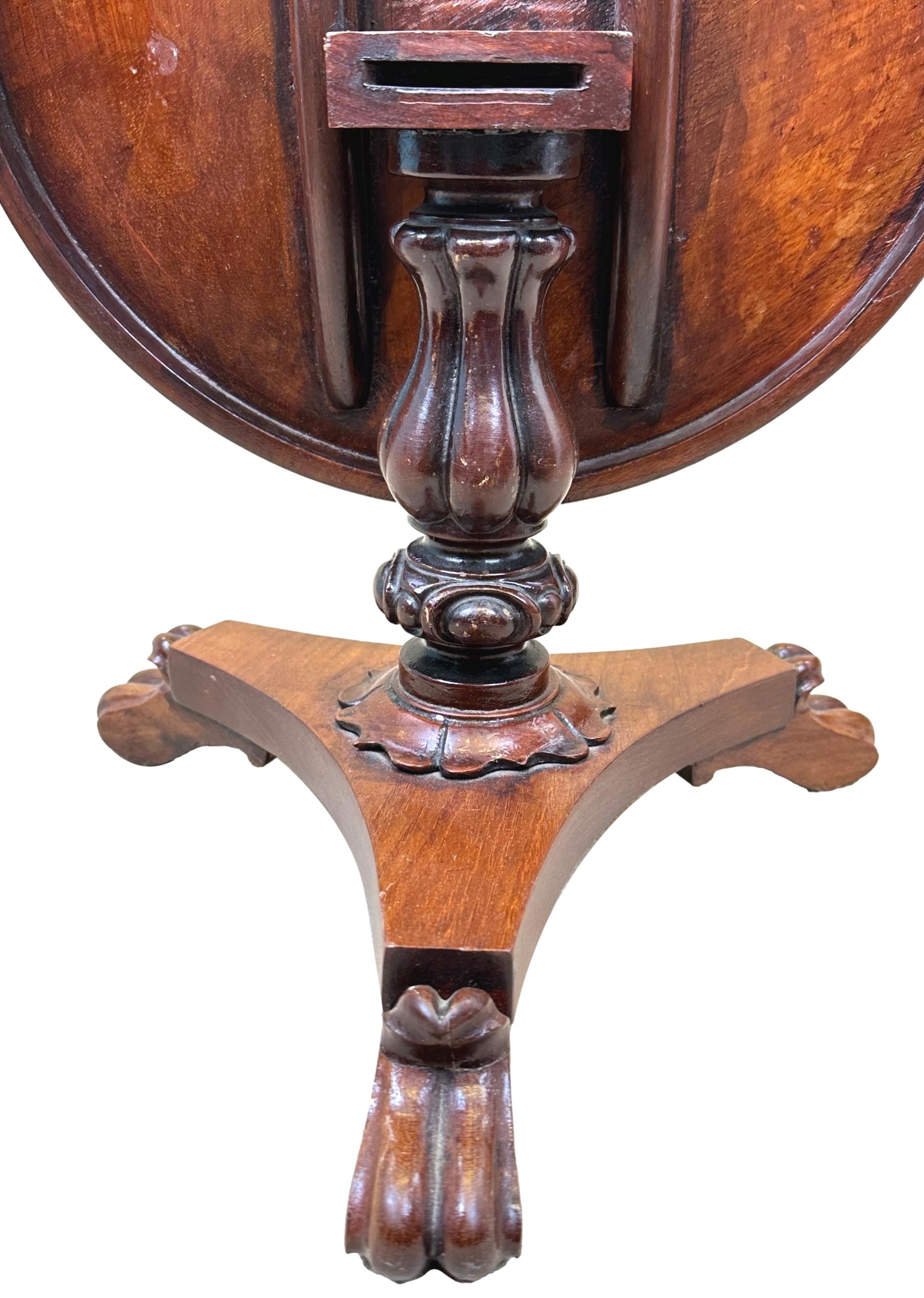 An exceptional quality mid-19th century mahogany miniature center table, having superbly figured circular tilting top, over elegant carved central column and triform plateau base, with carved scrolling feet.

There is often debate as to the