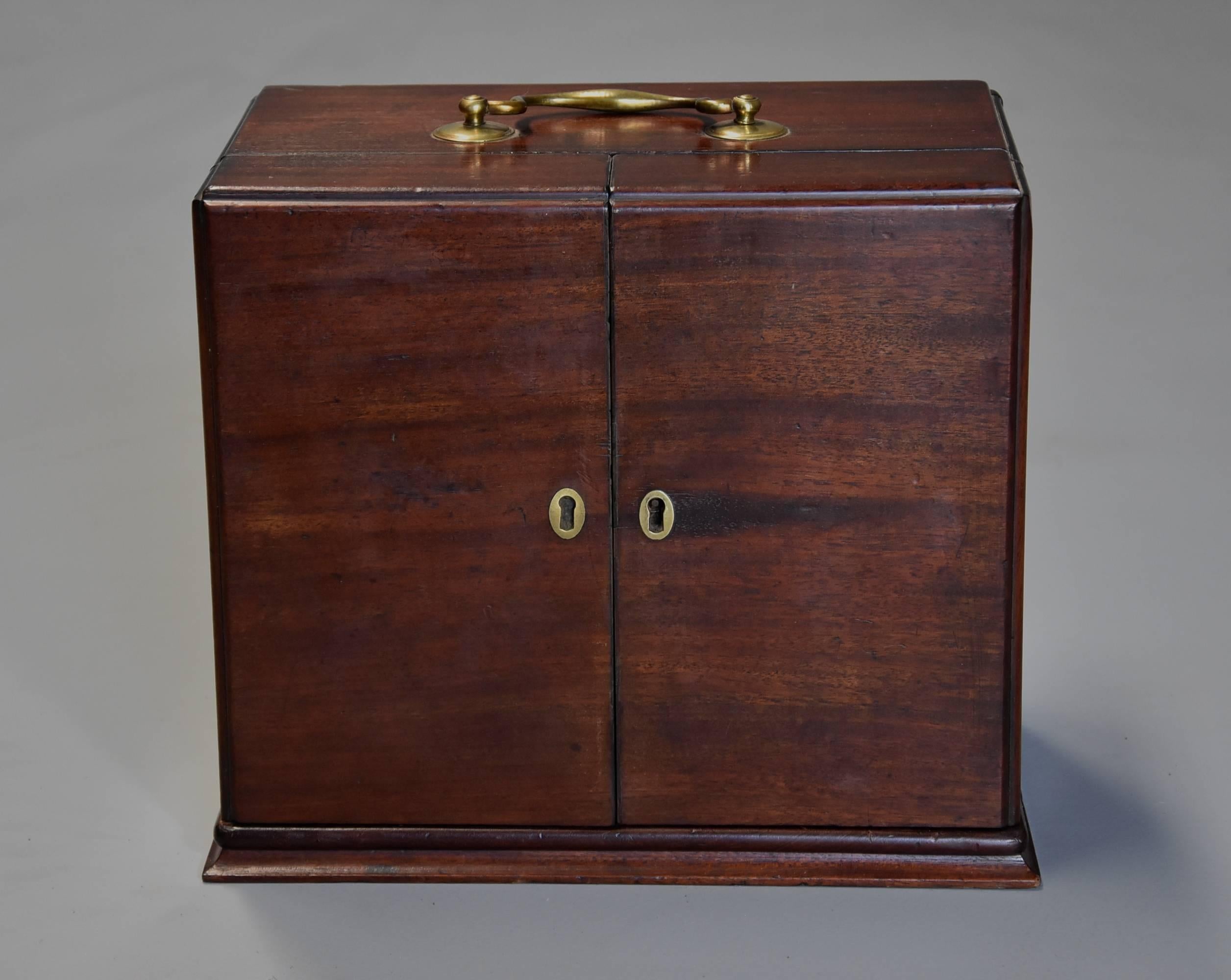 A mid-19th century (circa 1850) mahogany travelling apothecary cabinet.

This cabinet consists of a mahogany case with brass swan neck carrying handle to the top leading down to two doors with two oval brass escutcheons.

The doors opening to