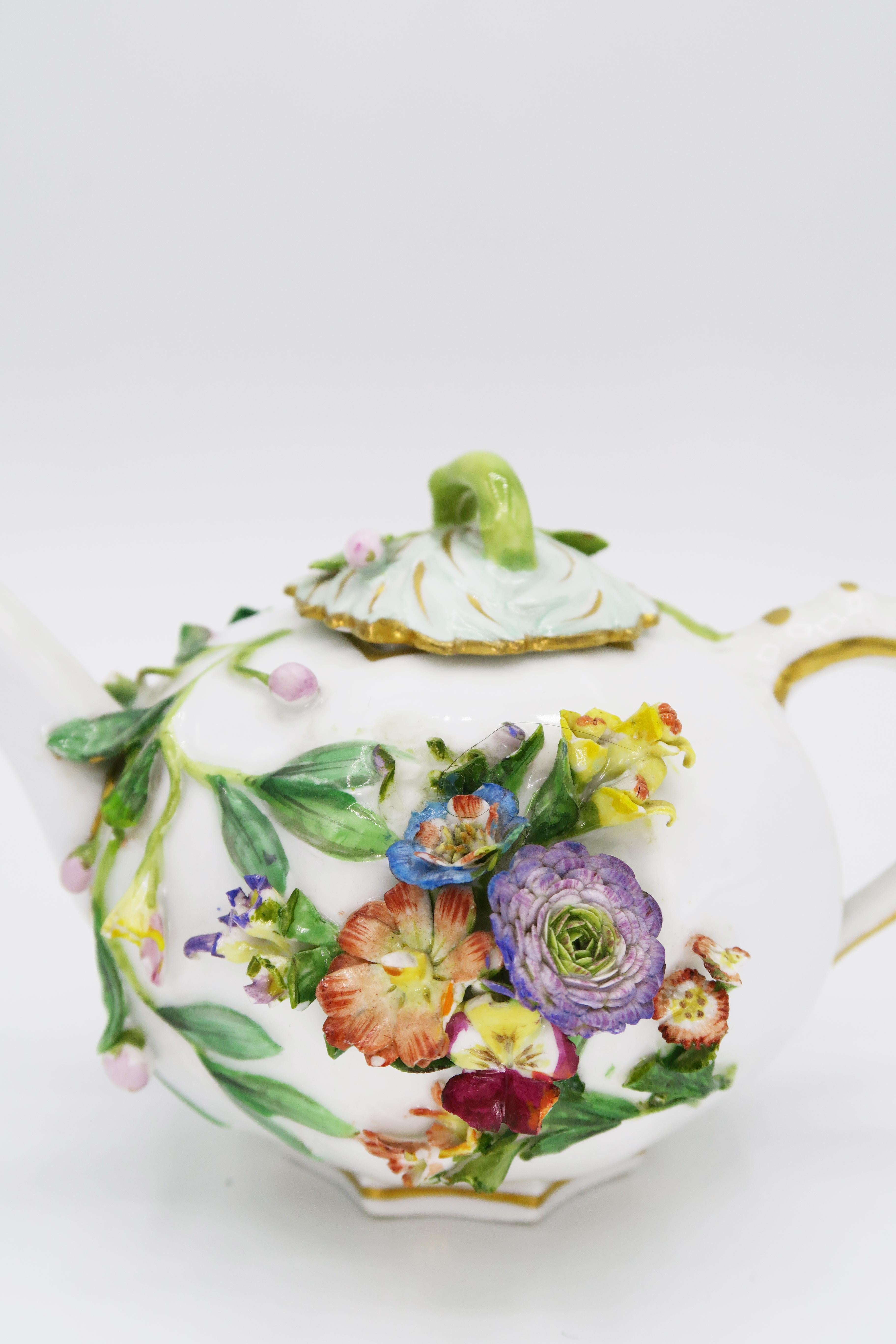 Pichet artisanal de Meissen du milieu du 19e siècle.

Forme hexagonale (hexagonale), corps bulbeux avec un bec tubulaire attaché et une poignée en forme d'oreille attachée.
Petit couvercle en relief avec un bouton.
Mur gaufré avec de fins