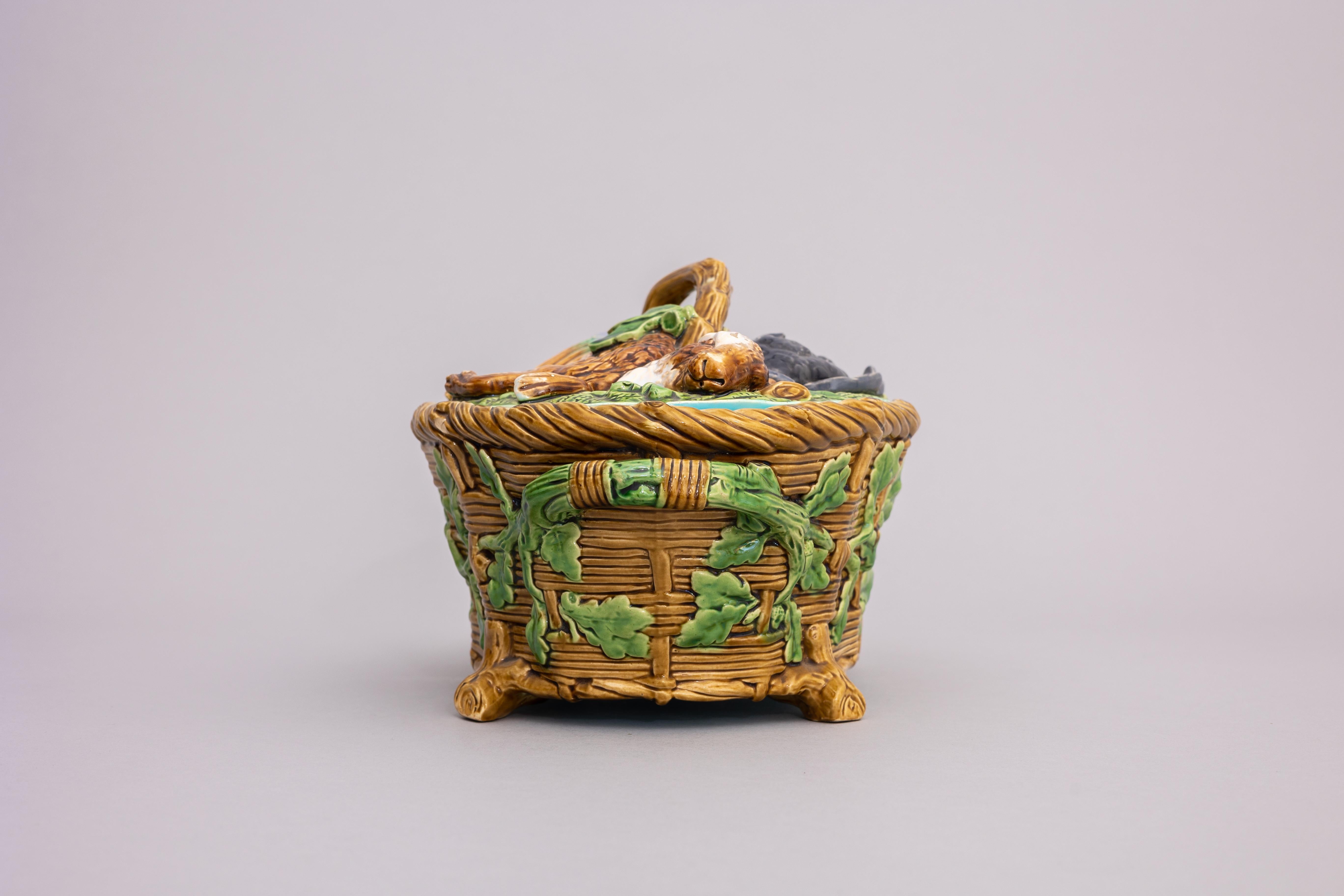 A majolica game pie dish made by Minton & Co. in 1864. The dish takes the form of a wicker basket and is covered with oak leaves, acorns, vines, and ferns. The dish’s lid features a group of realistically molded dead game: a rabbit, a mallard, and a