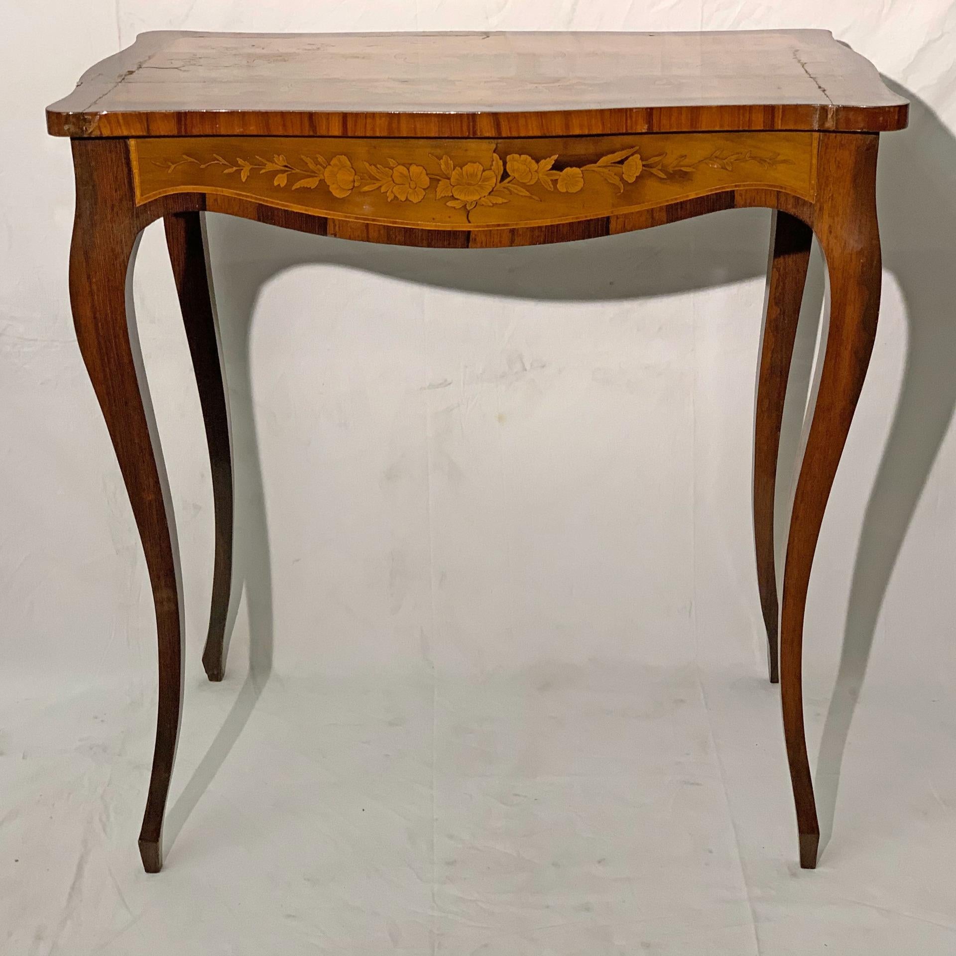 Magnifique table basse en bois entièrement décorée de fines incrustations de bois précieux tels que le noyer, l'olivier et le rosier. Les incrustations concernent des détails floraux présents sur le plateau et les côtés, qui donnent une touche