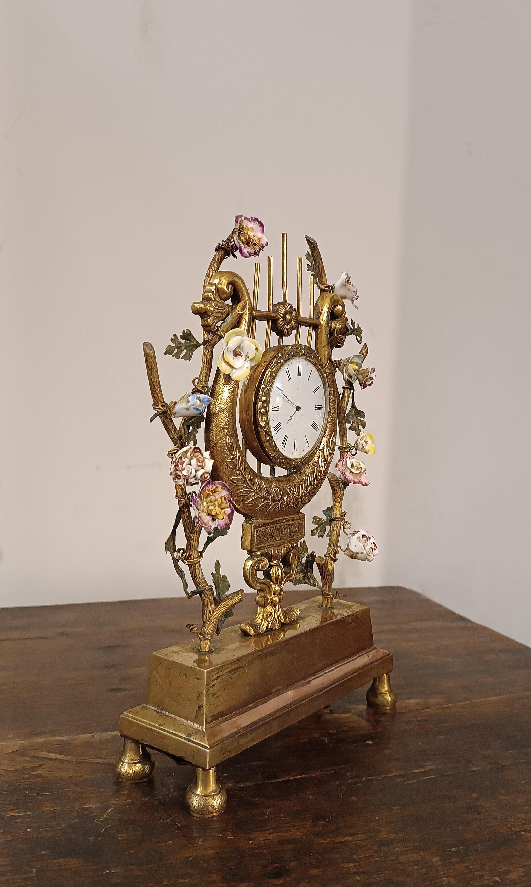 Splendid and refined lyre clock in gilded bronze, with spring winding. Its decoration with plant racemes and small roses in Meissen polychrome porcelain gives a touch of elegance and class to the clock. Despite its small size, this clock is able to