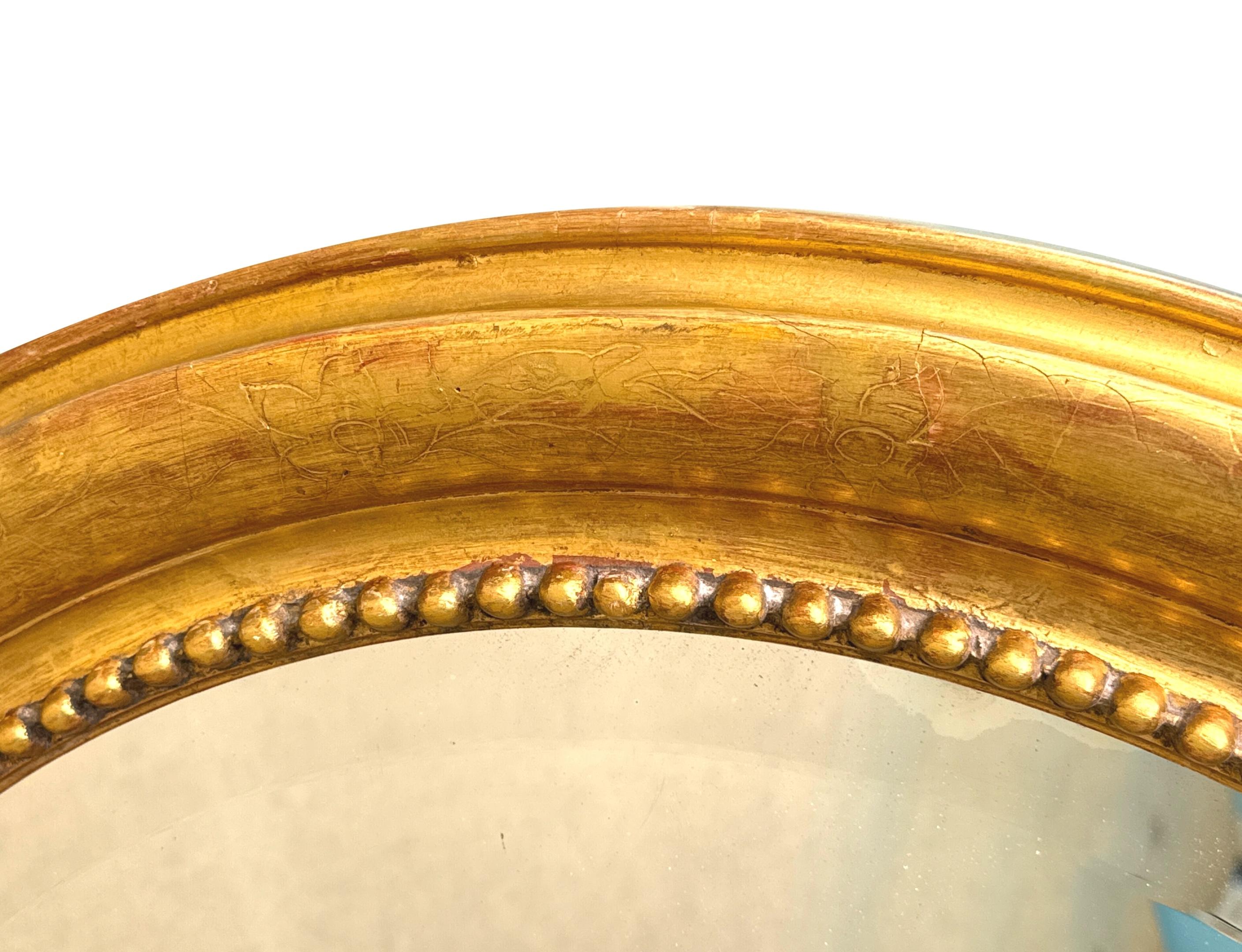Specchio da parete ovale in legno dorato della metà del XIX secolo, di buone proporzioni, con eleganti decorazioni incise a fogliame e bordo a bolle d'aria sulla cornice, che racchiude il piatto originale dello specchio smussato. 

Questo specchio è