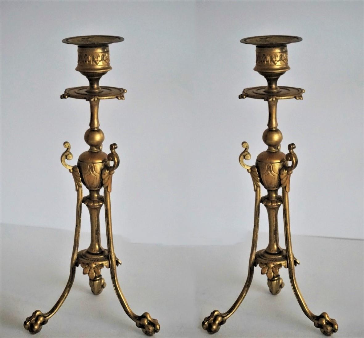 A pair of Empire style gilt bronze candlesticks raised on three lions paws, France mid-19th century.
  