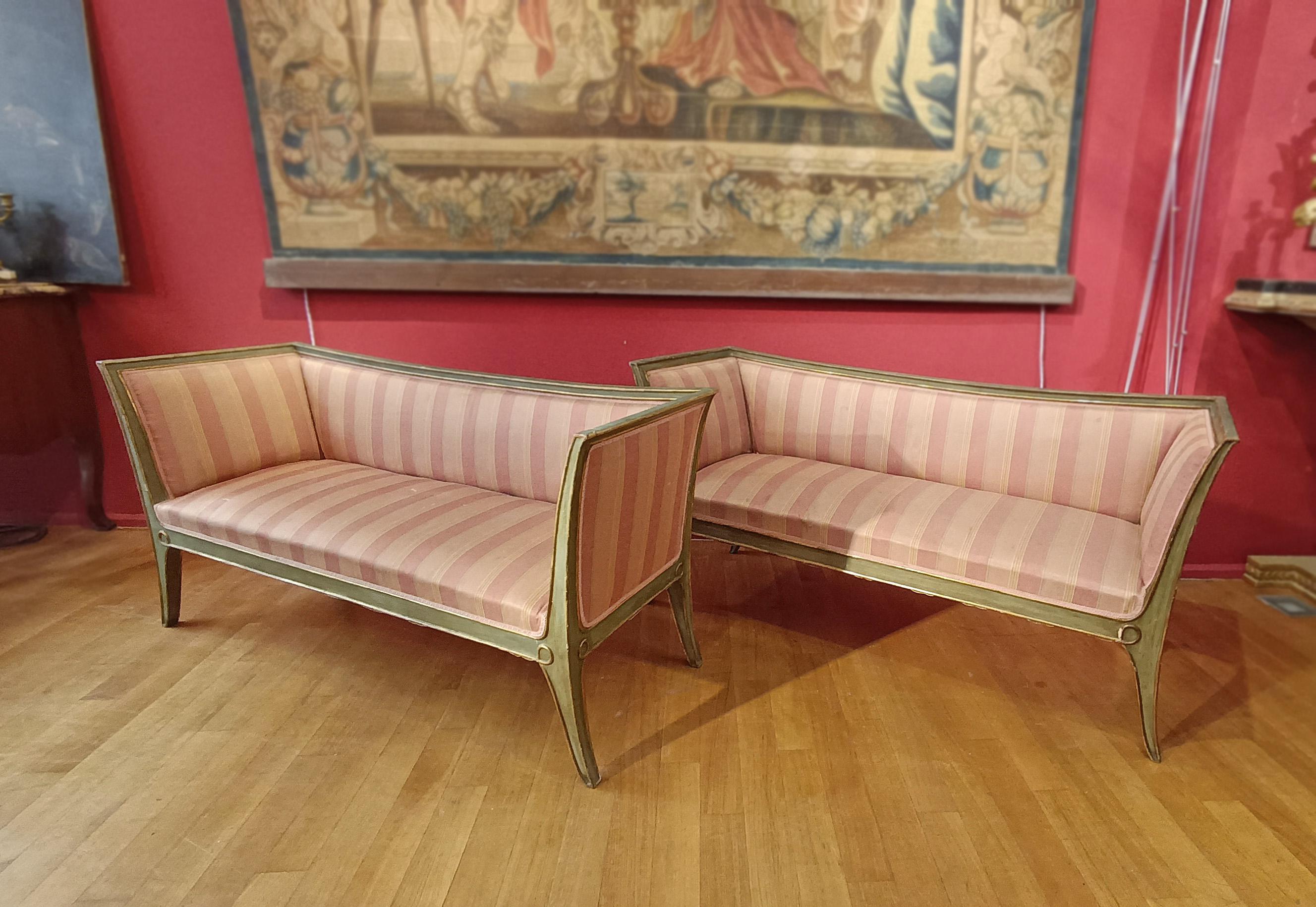 Elegant pair of carved, lacquered, and gilded wood sofas with pure gold leaf. These Directoire-style sofas feature curved legs and sides that lend a refined touch. The green lacquer finish is enriched with gilded details and geometric decorations.