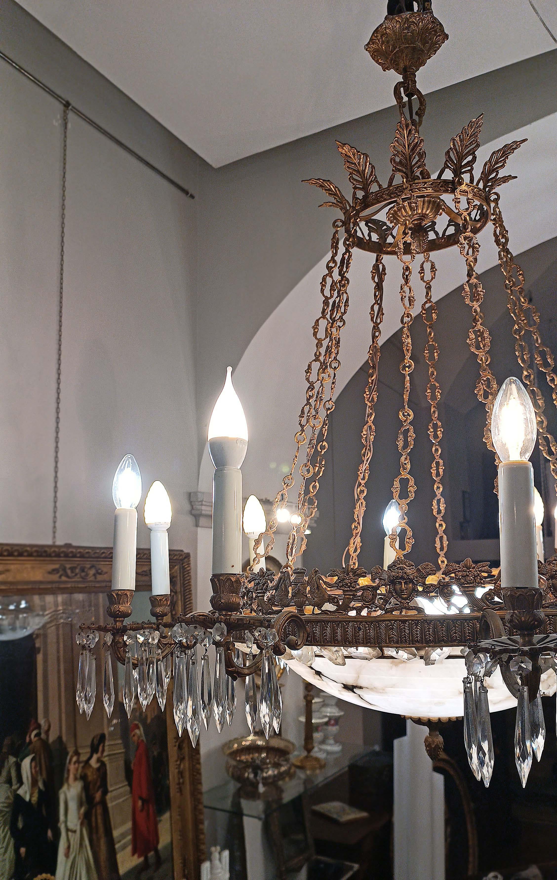 Elegante pareja de lámparas de araña de nueve luces, con refinados detalles y cadenas de bronce dorado. La banda presenta palmetas, rasgo típico de la época del Primer Imperio, mientras que los adornos florales, enriquecidos con cornucopias y