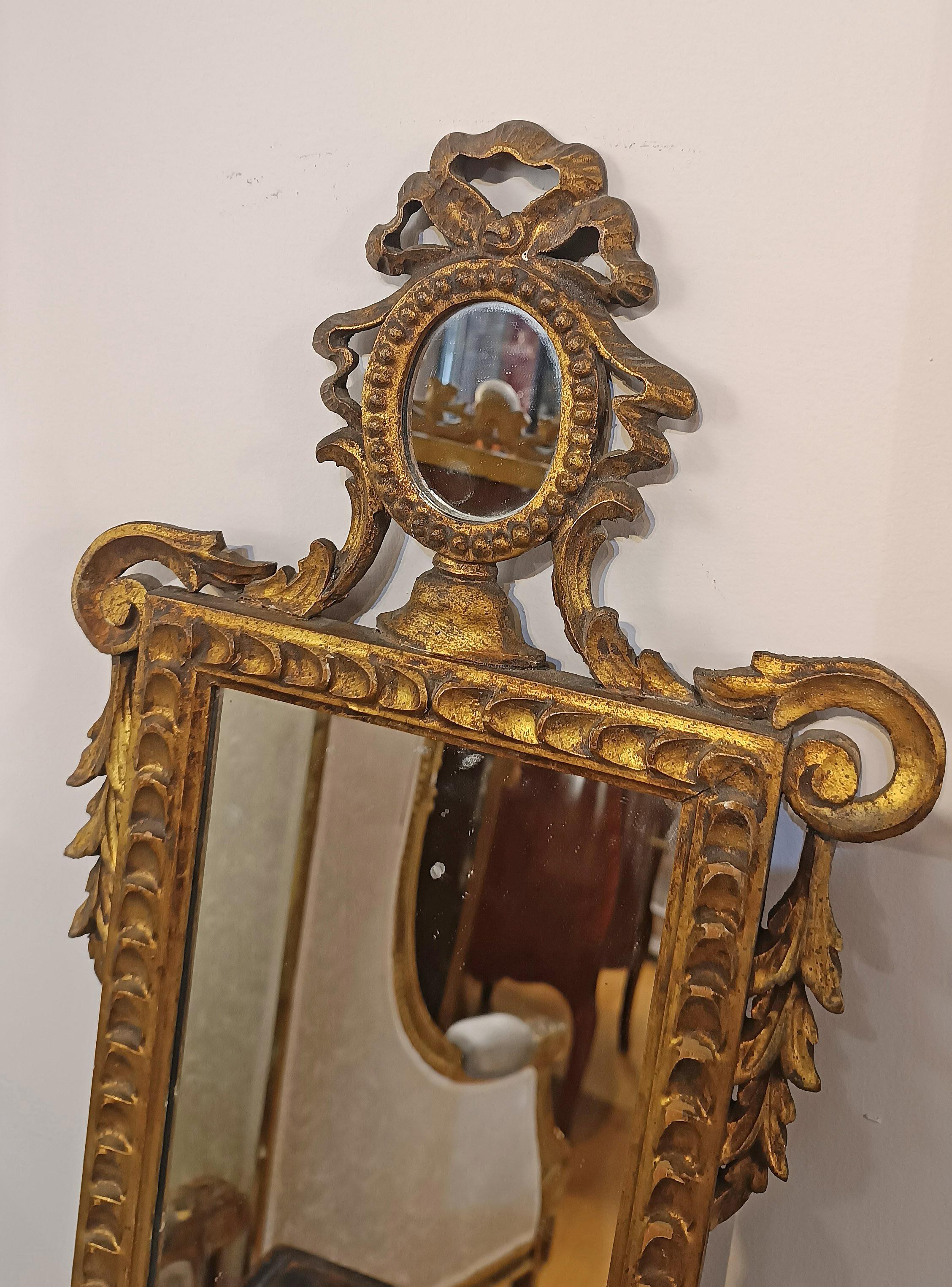Elegantes Paar kleiner Spiegel, aus geschnitztem Kiefernholz gefertigt und mit Blattgold verziert. Die Spiegel sind im oberen Teil mit Pflanzenmotiven verziert und gipfeln in einem bogenförmigen Cymatium mit einem kleinen Spiegel. Im unteren Teil