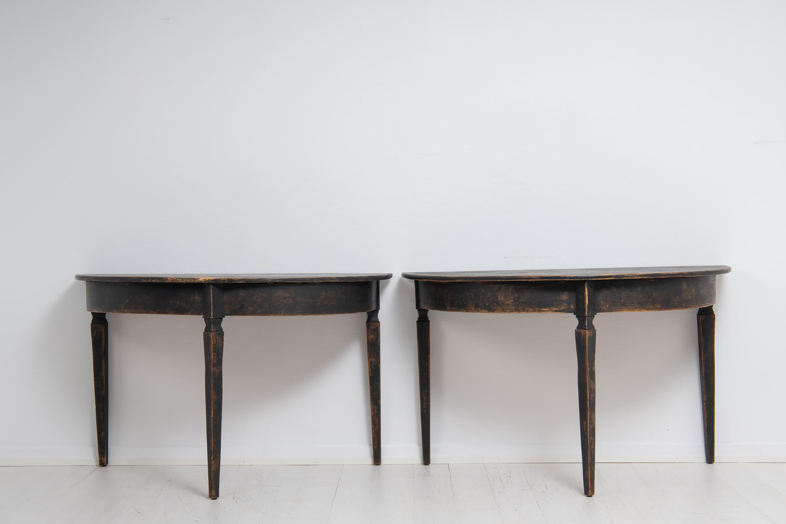 Pair of black demi lune tables from northern Sweden made during the mid 19th century. The tables are from around 1860 and has black distressed paint. The tables have minimal adornments for a very clean and minimalistic look. The paint gives it