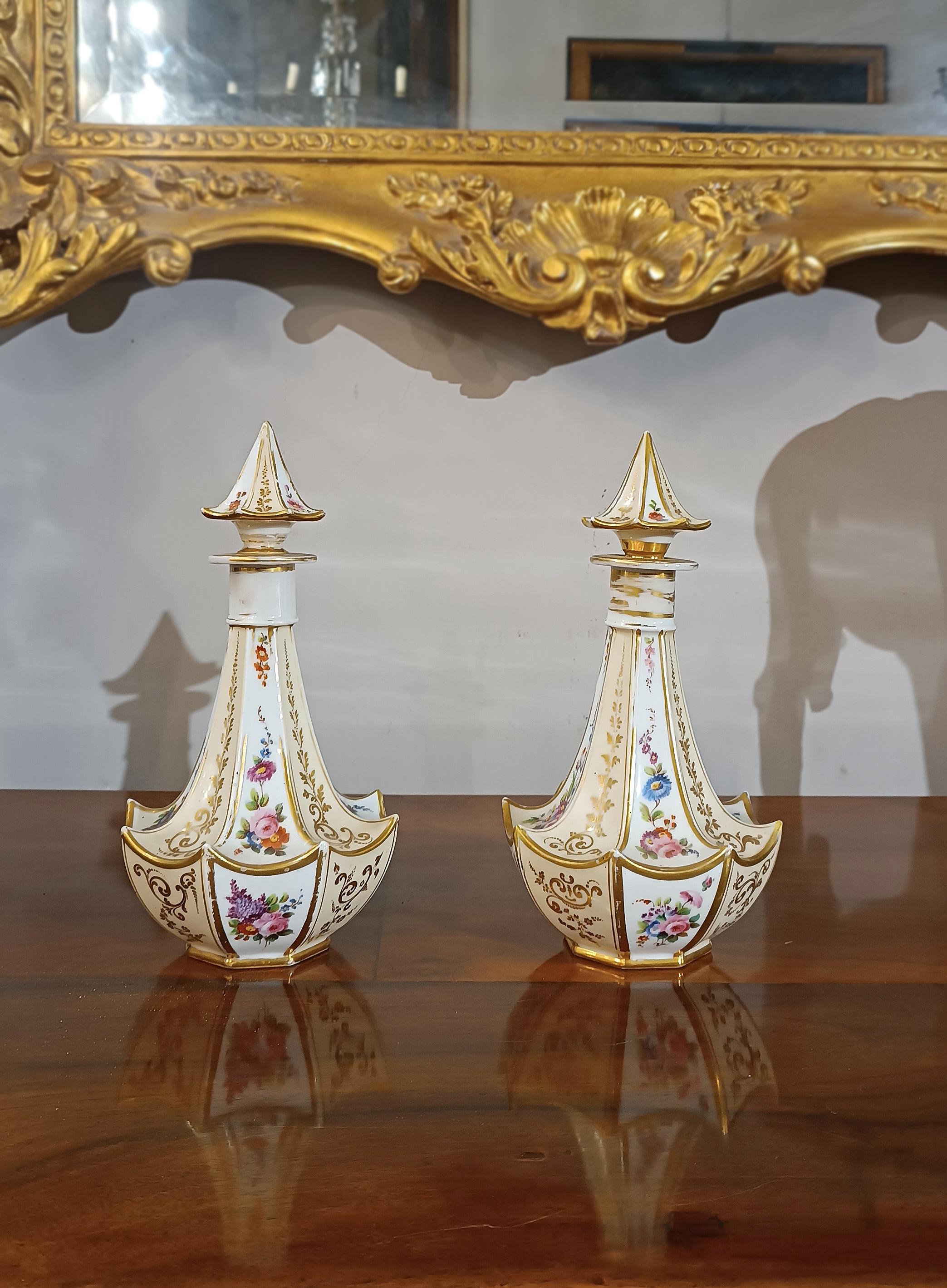 Elegant pair of perfume bottles in white porcelain, embellished with polychrome and gold finishes. The gold finishes, decorated with vegetal swirl motifs, give these bottles a timeless elegance and refinement. The polychromy of the colors, used in